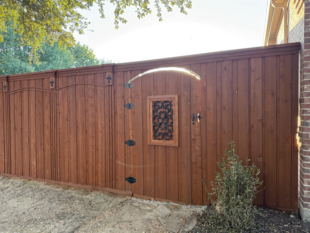 Stained fence with decorative iron scroll gate