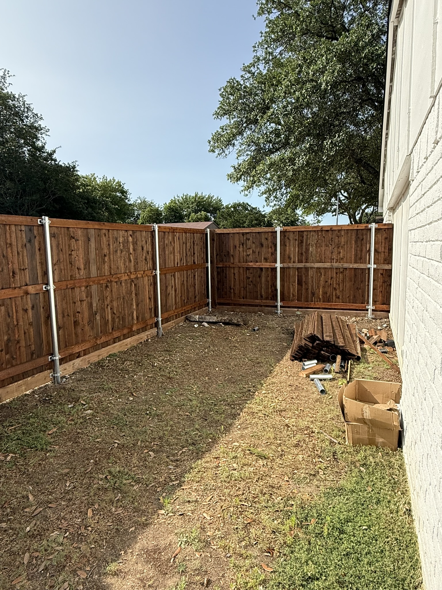 Cedar privacy fence with metal posts under construction in a backyard corner