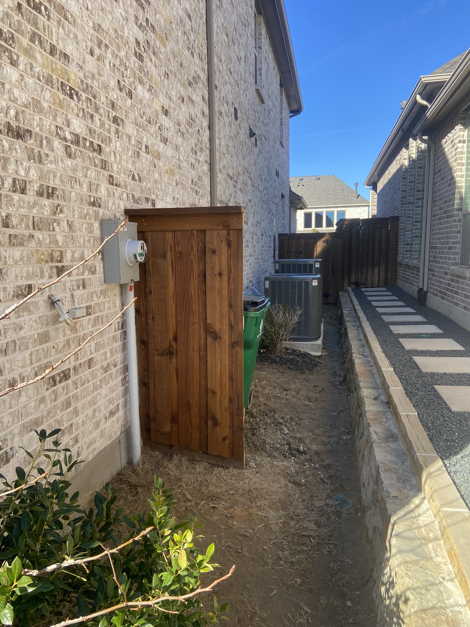 Cedar wood gate in a narrow side yard between two brick houses
