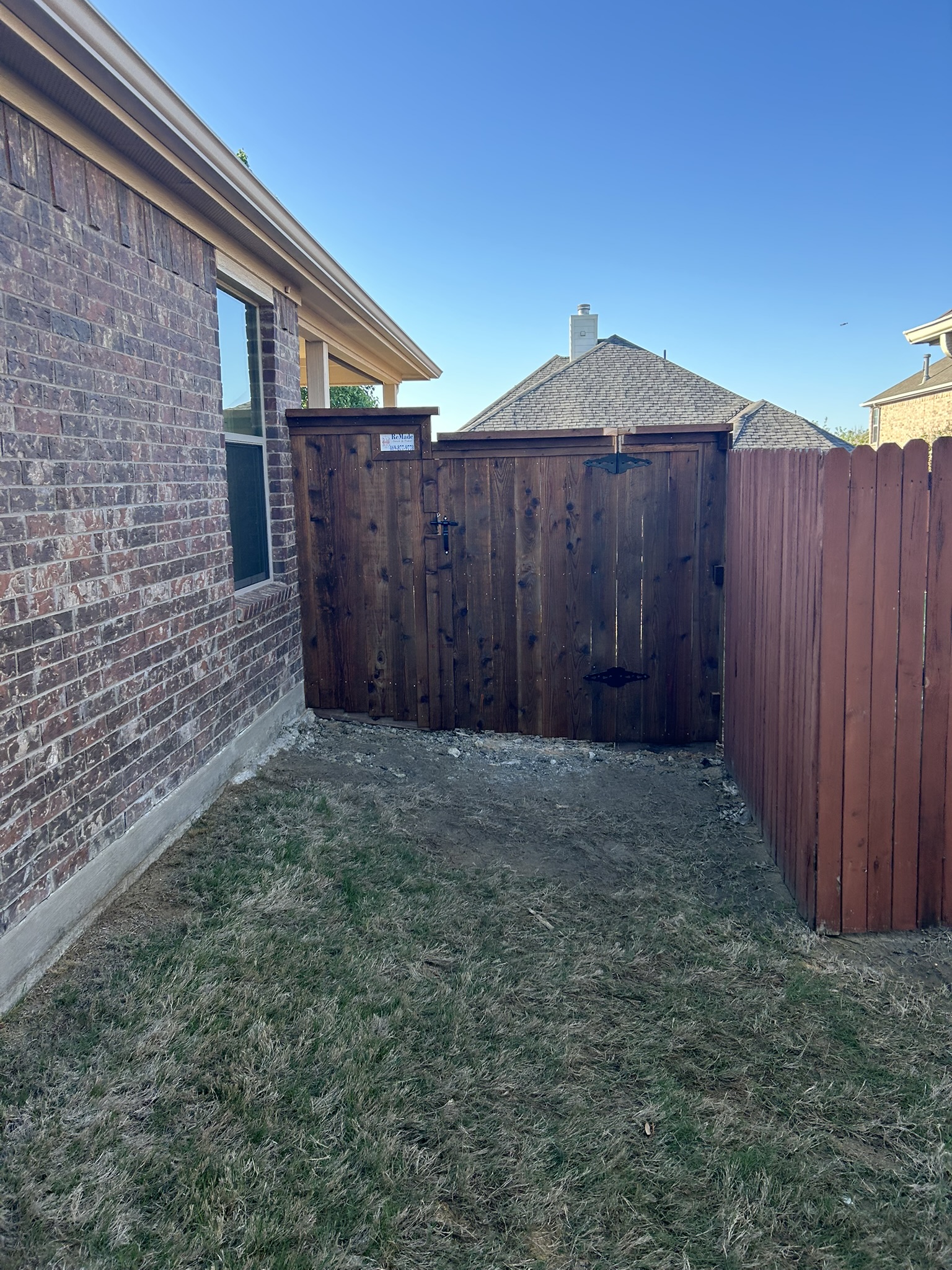 Stained cedar privacy fence and gate between brick homes in a backyard