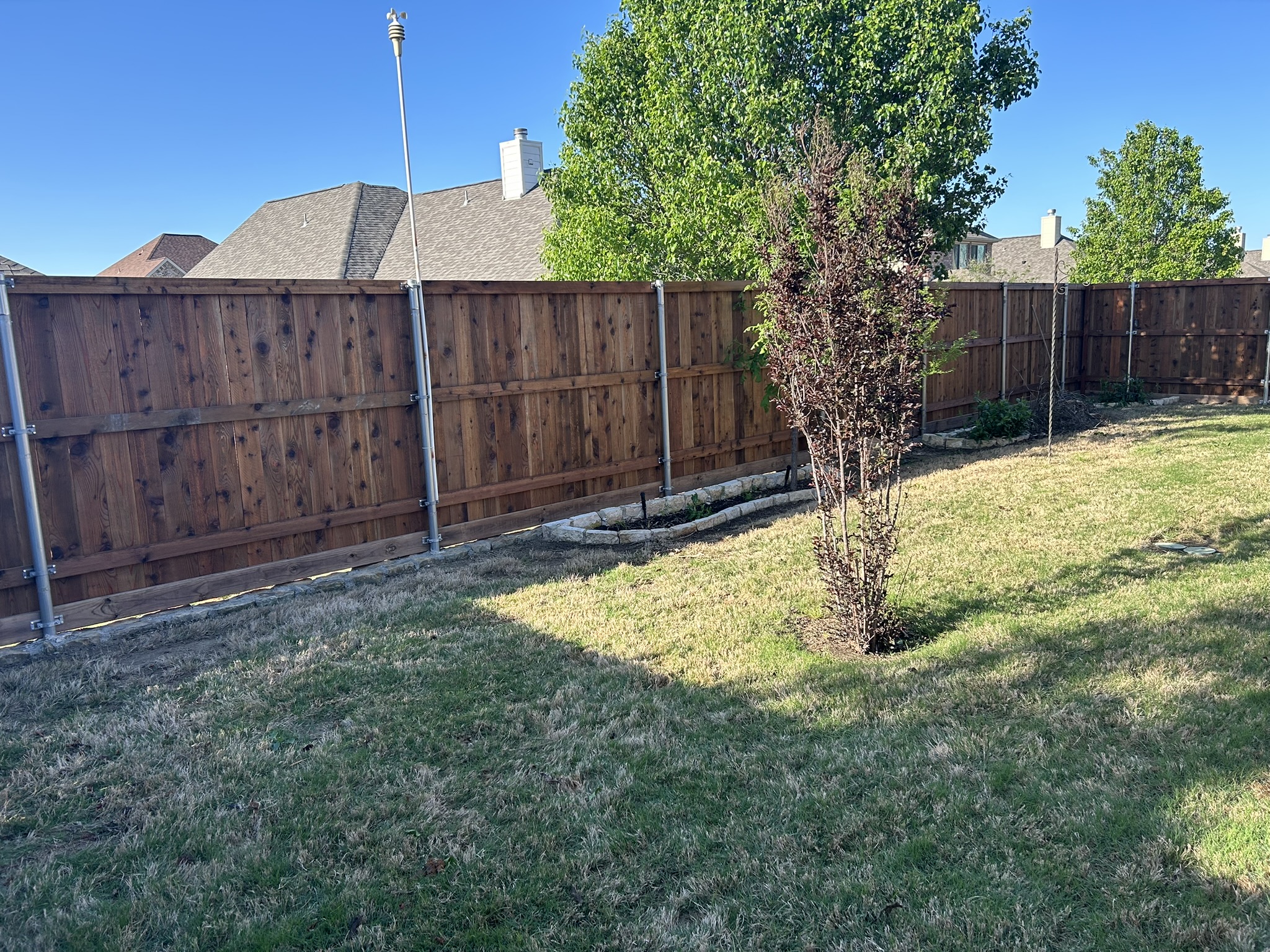 Cedar board-on-board privacy fence with metal posts along a backyard