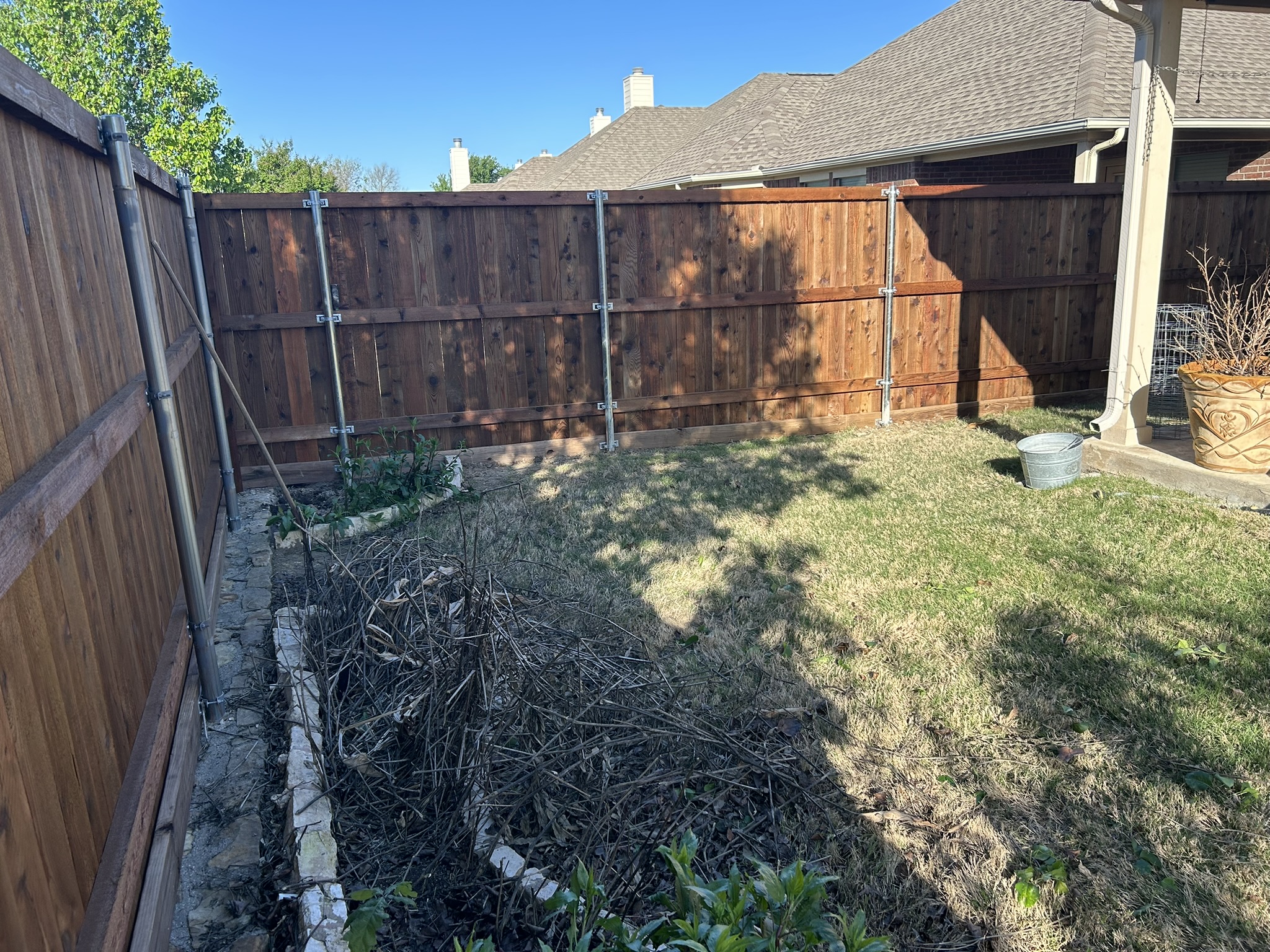 Stained cedar privacy fence corner with metal posts in a residential backyard