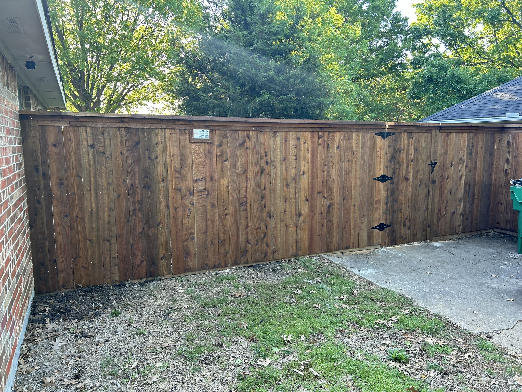 Stained cedar privacy fence with gate and black hardware in a backyard