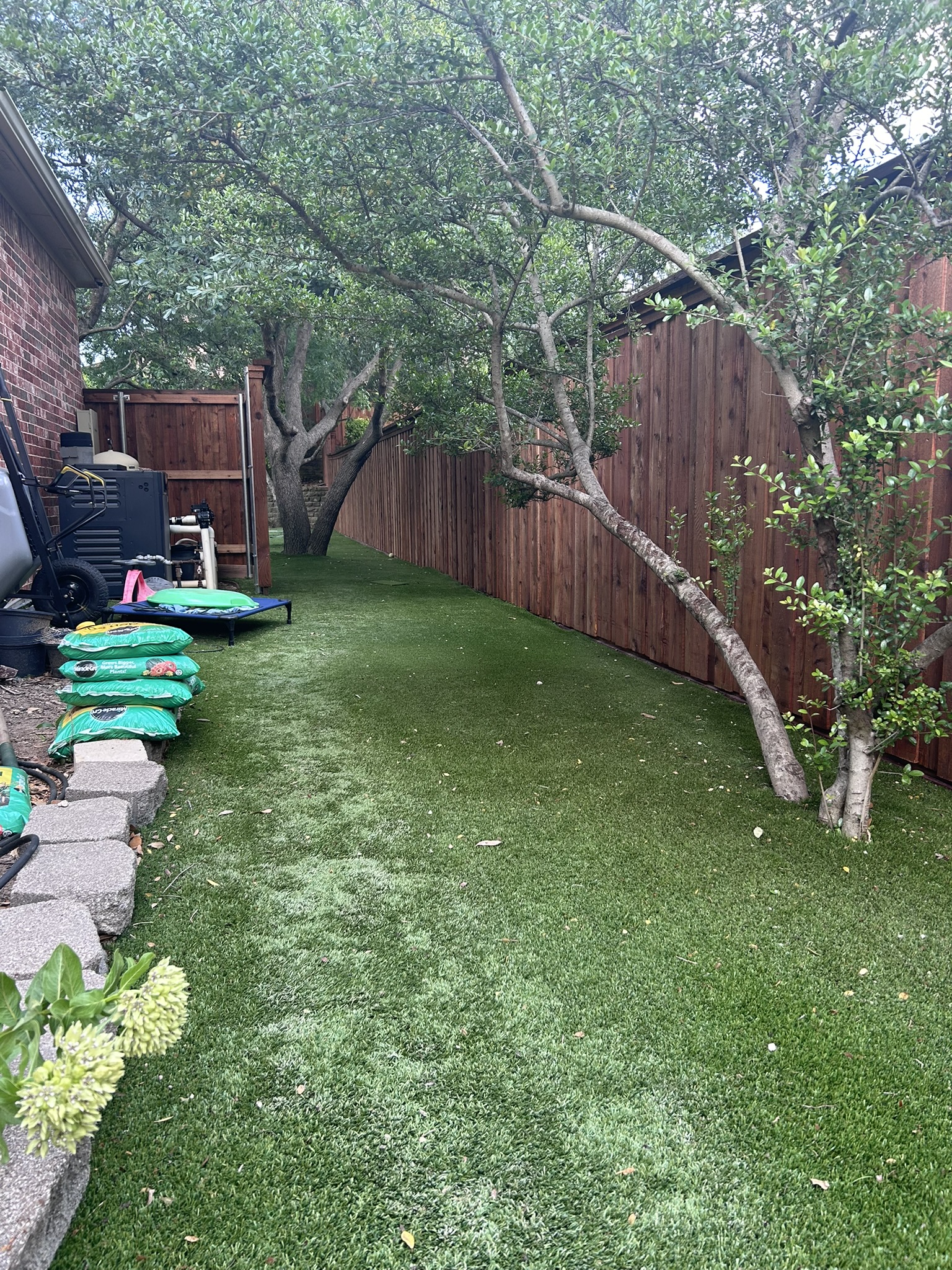 Stained cedar privacy fence along a side yard with artificial turf and mature trees