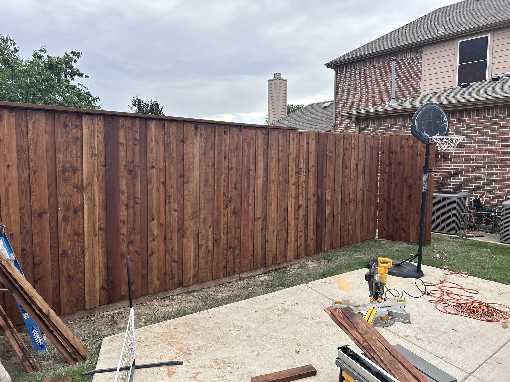Newly built stained cedar board-on-board privacy fence in a backyard
