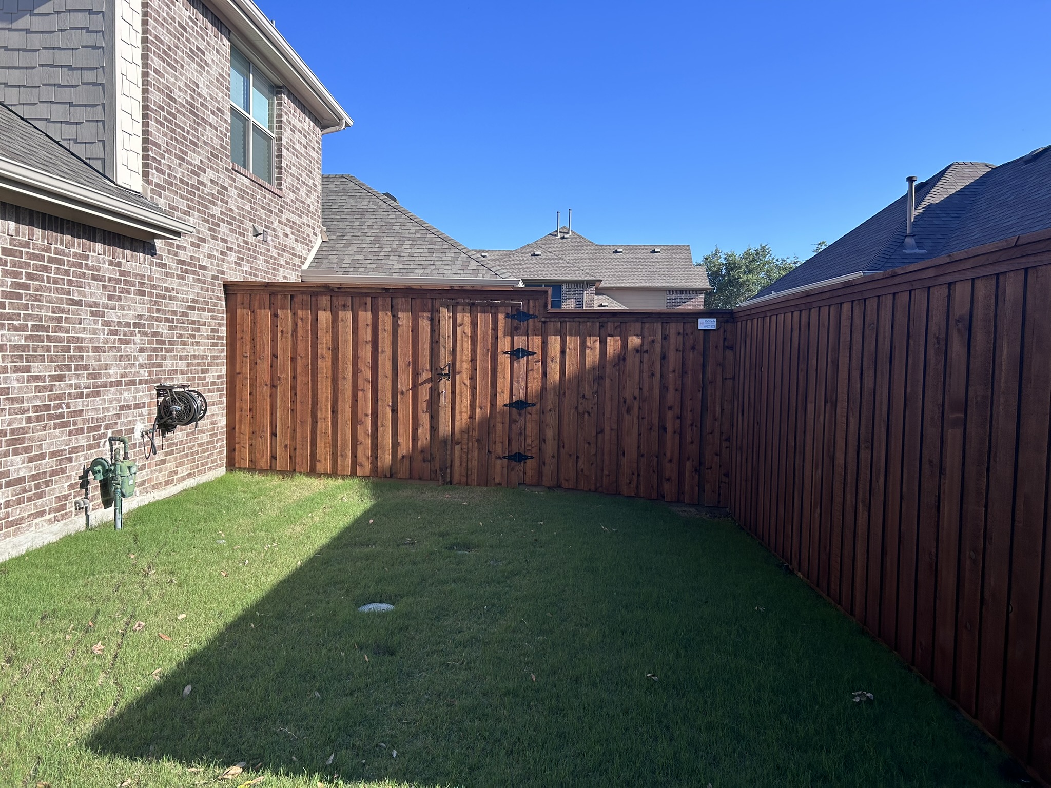 Stained cedar privacy fence with matching wood gate and decorative iron hinges