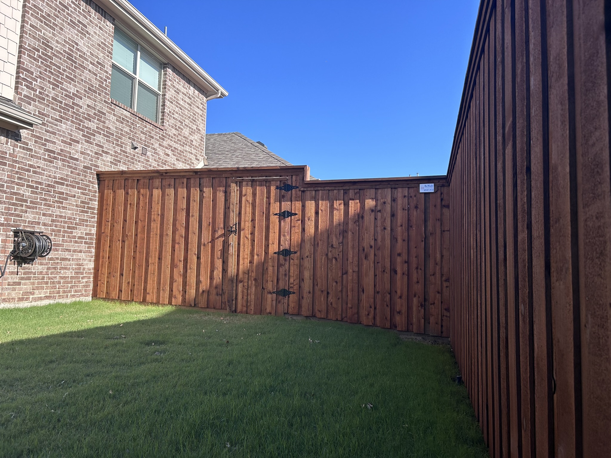 Stained cedar privacy fence and gate with decorative iron hardware