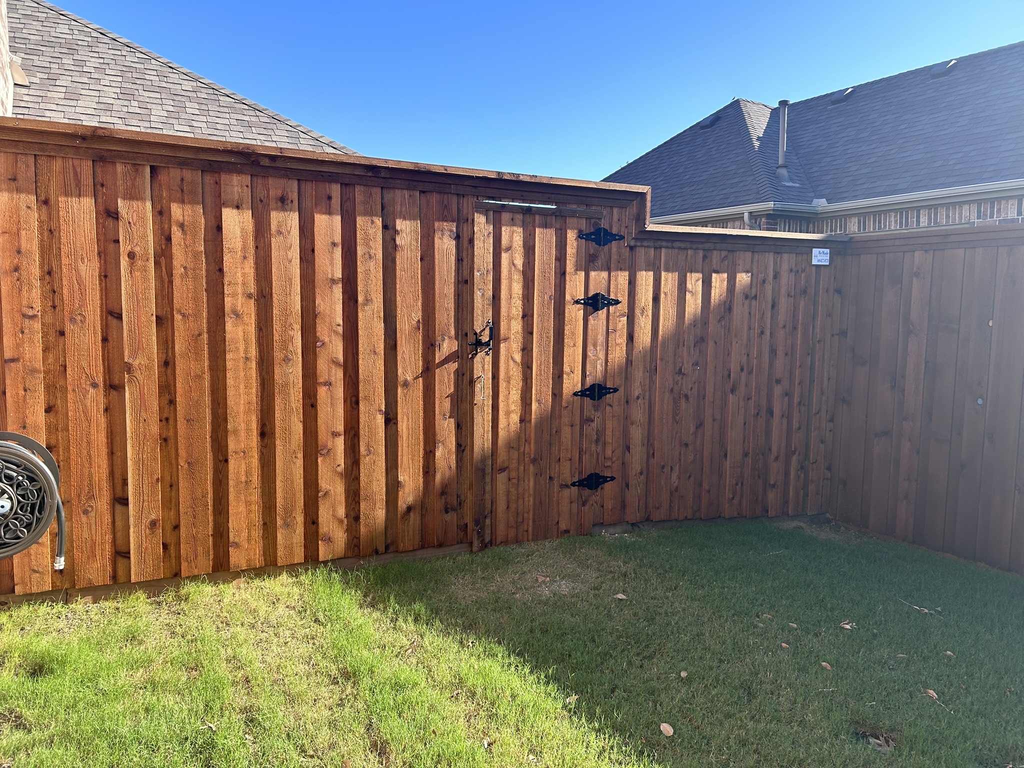 Stained cedar privacy fence with gate and decorative iron hardware in a side yard