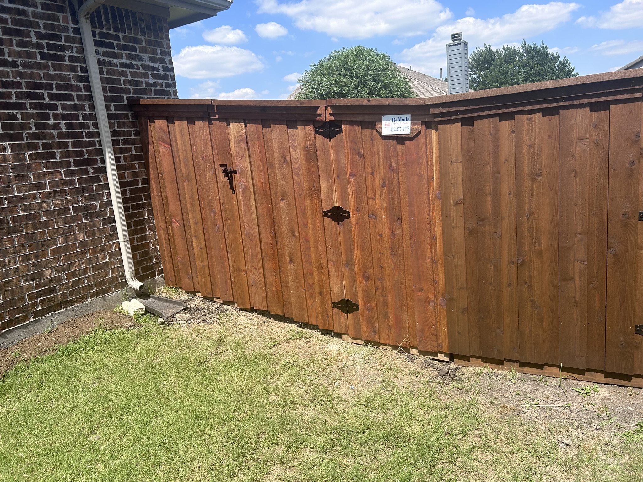 Stained cedar privacy fence and gate with decorative iron hardware from side angle