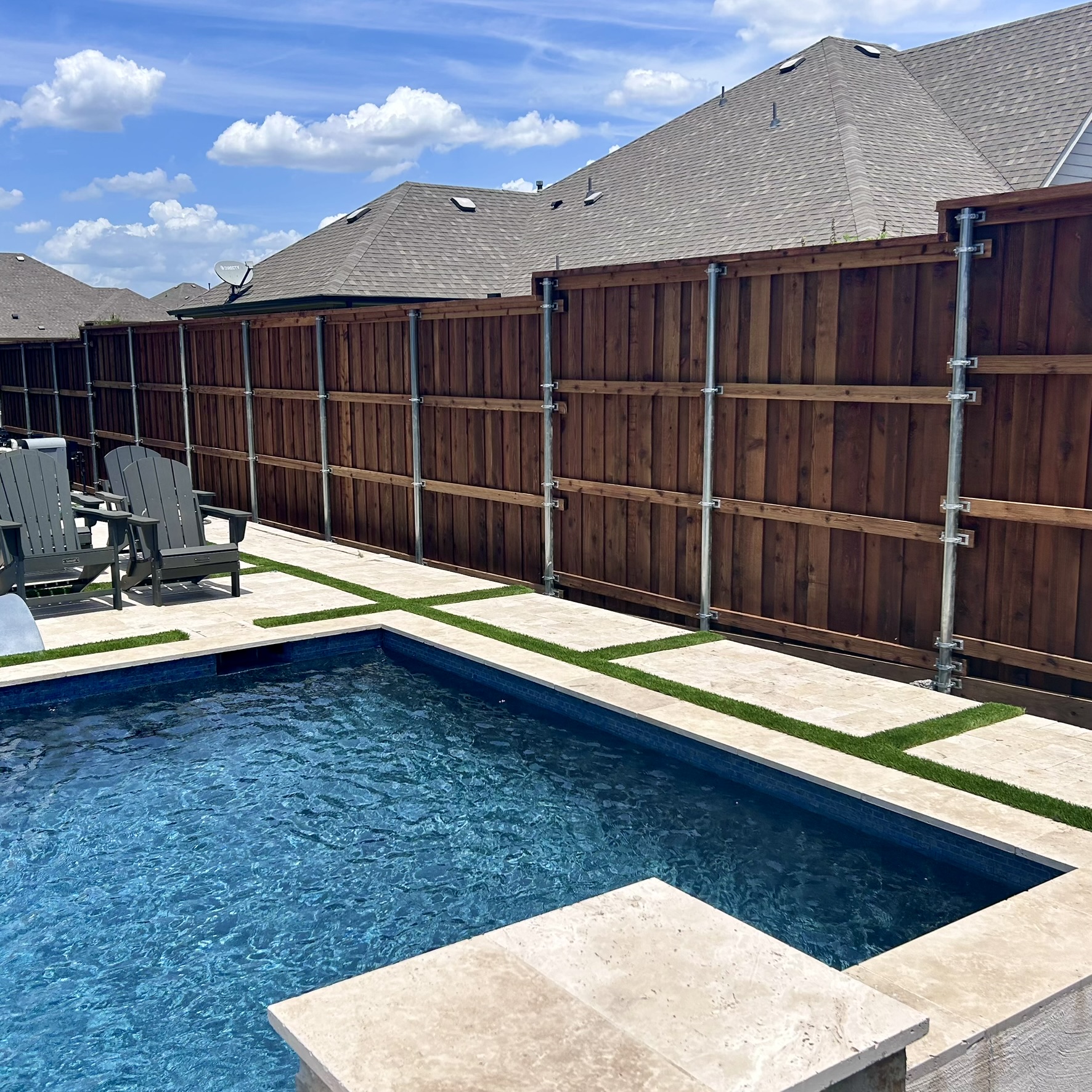 Stained cedar board-on-board privacy fence with metal posts surrounding a pool area
