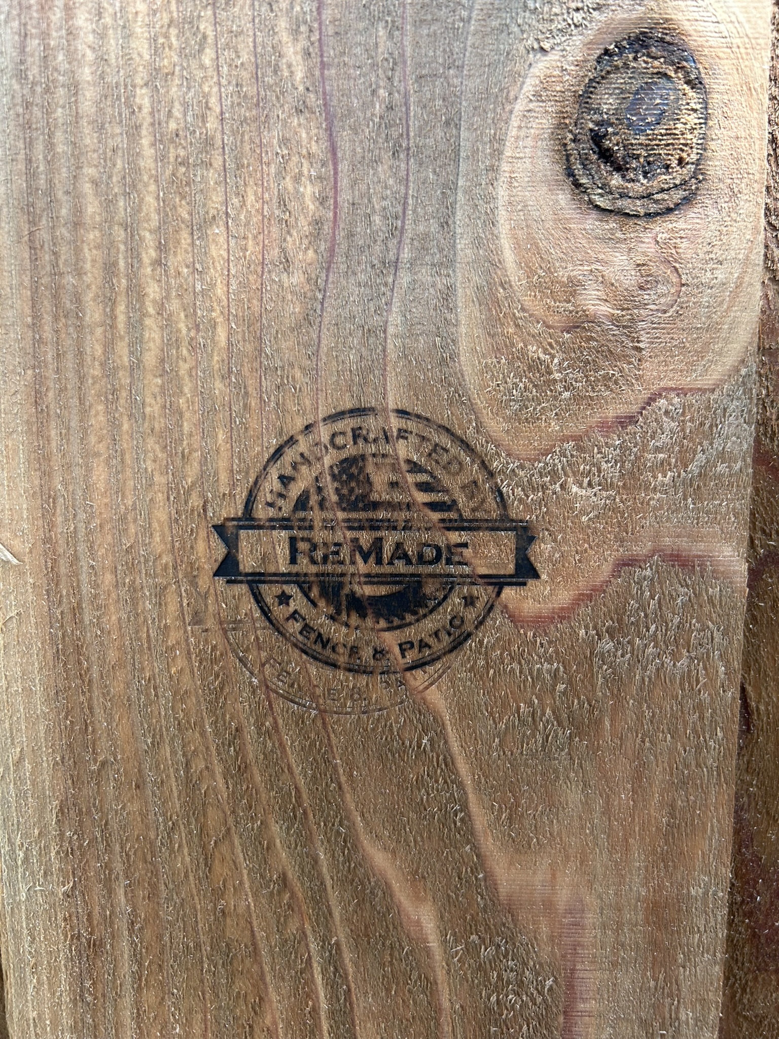 Close-up of ReMade Fence and Patio branded stamp burned into a cedar fence board