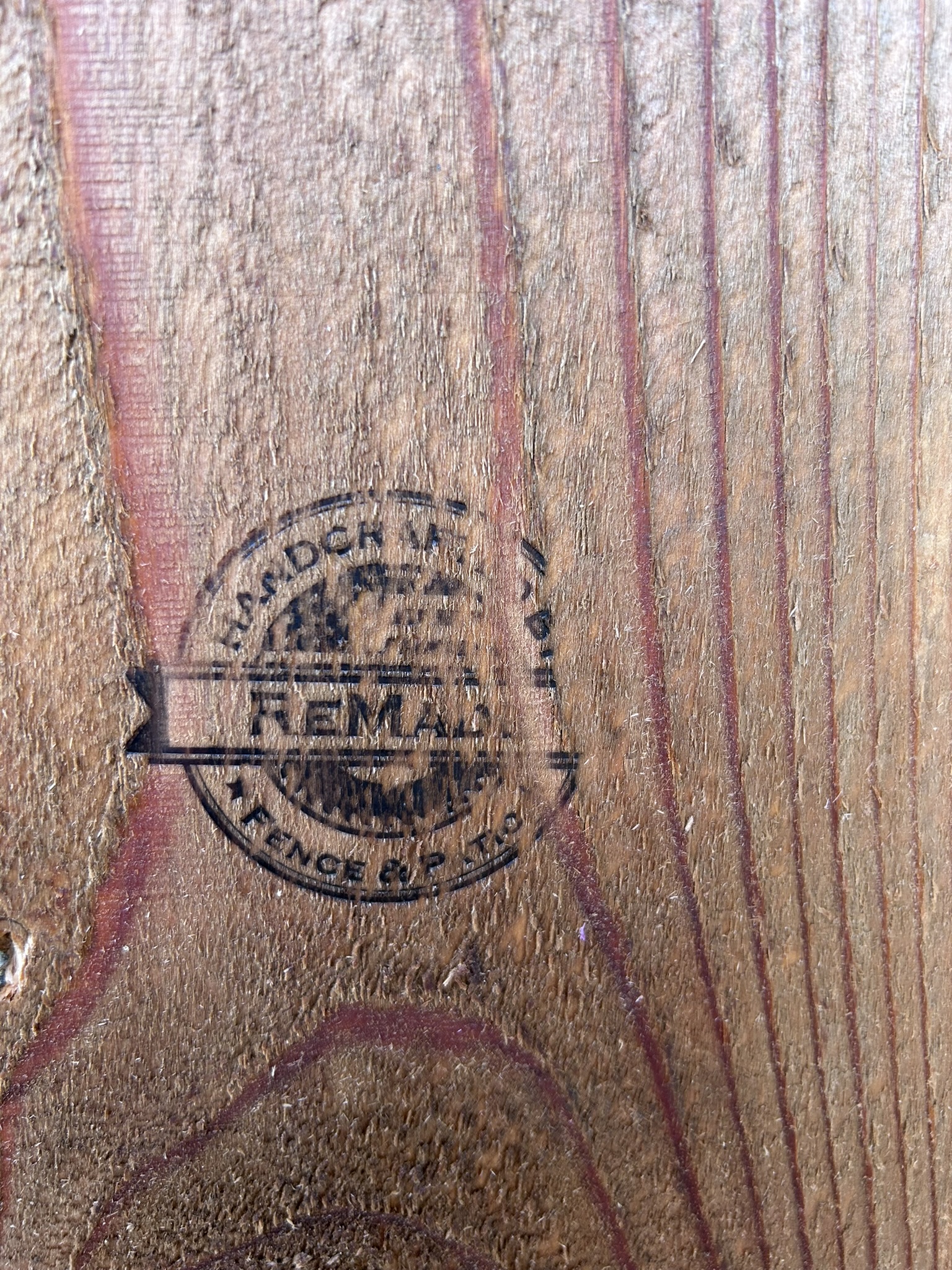 Close-up of ReMade branded stamp burned into a stained cedar fence board