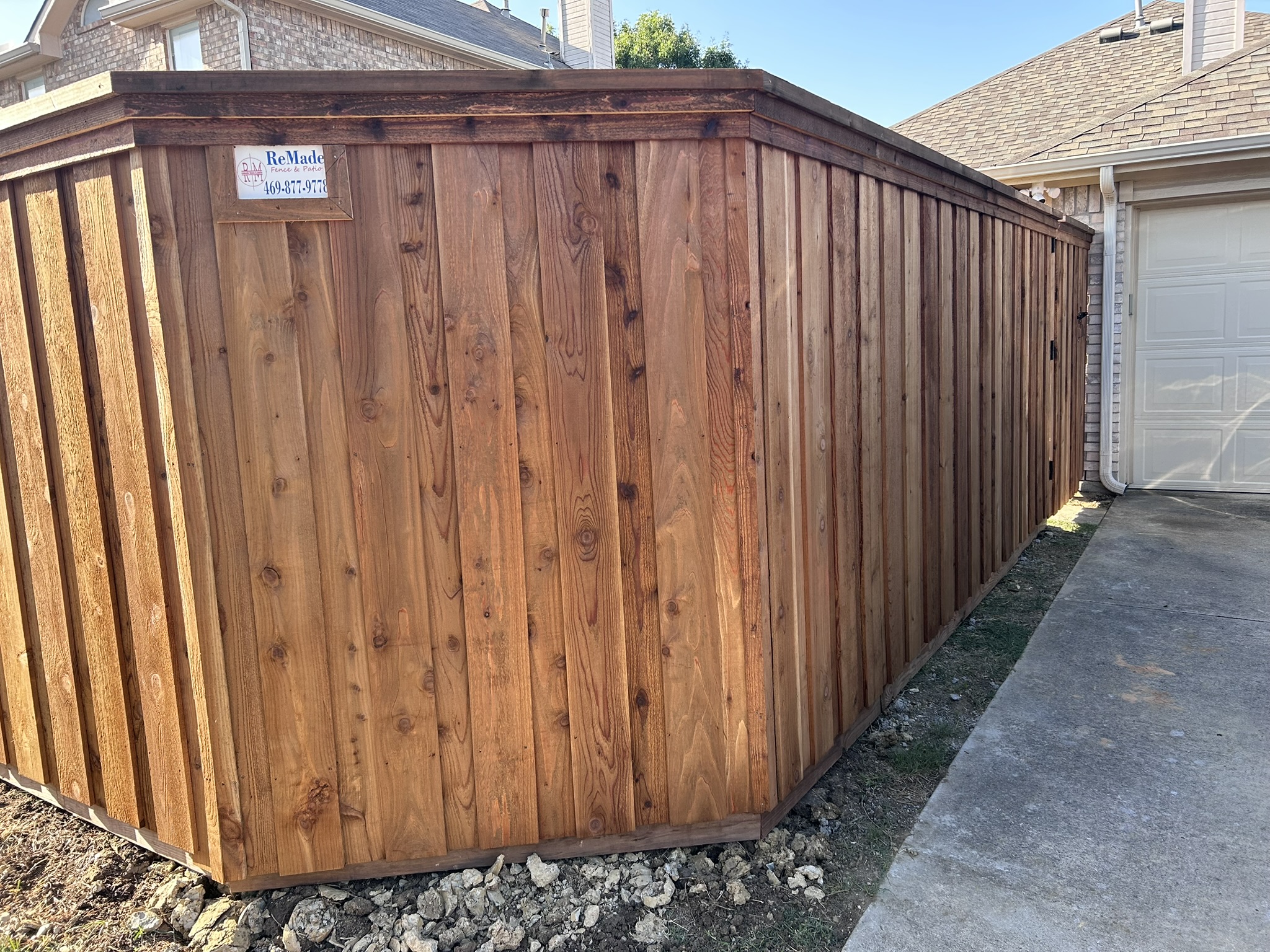 Stained cedar board-on-board privacy fence corner view near a garage