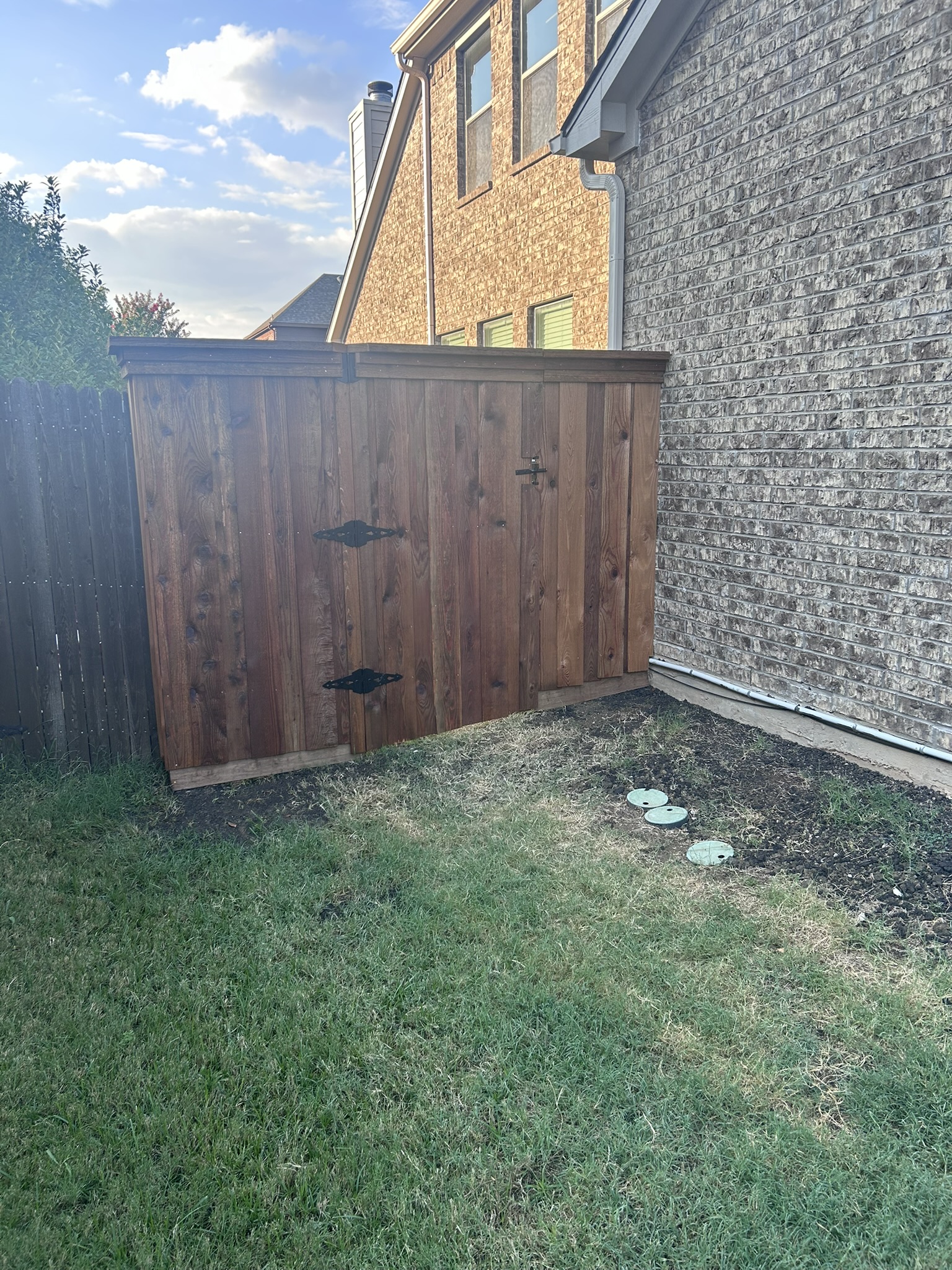 Dark stained cedar privacy fence and gate with decorative iron hardware
