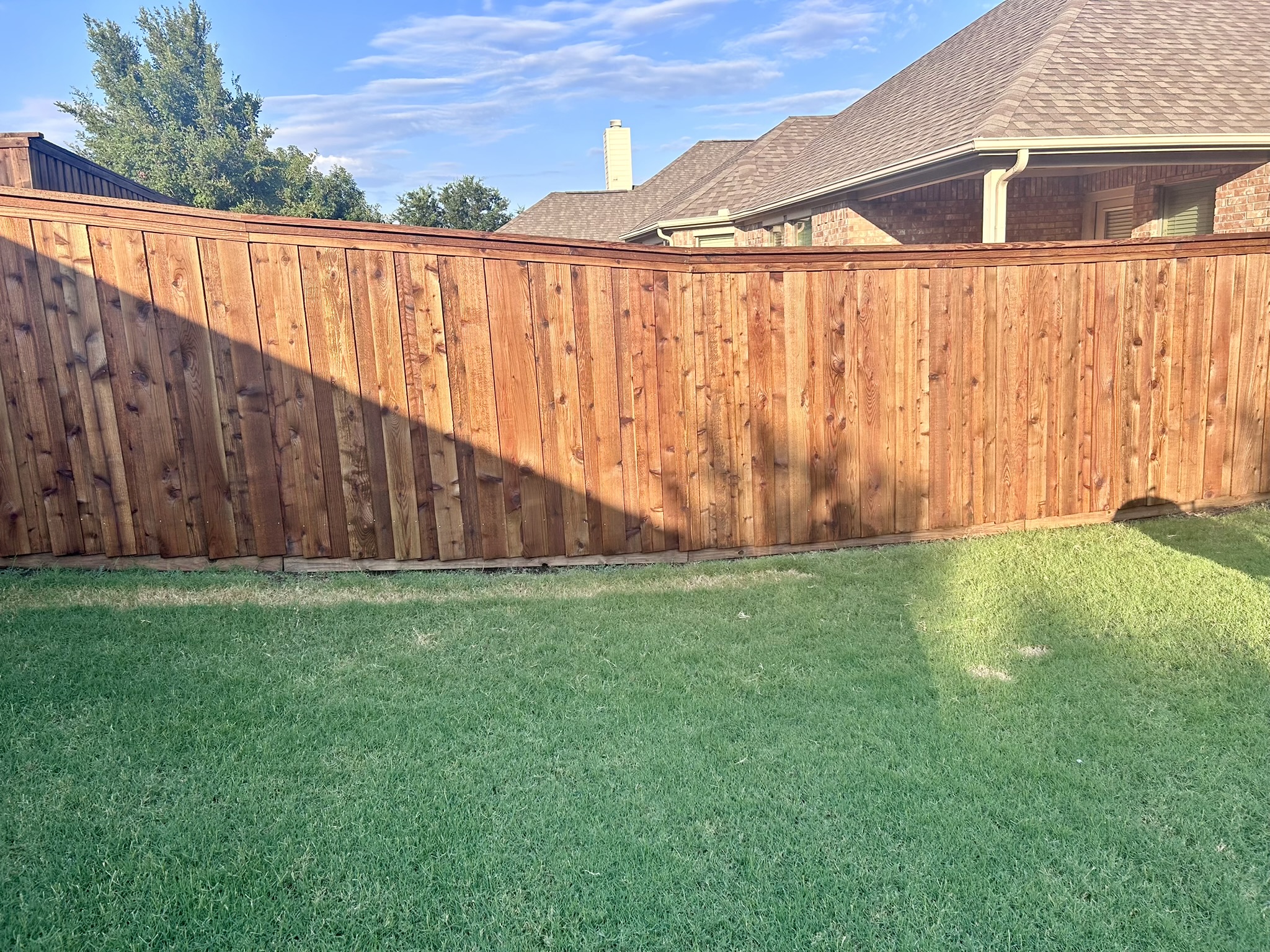 Long cedar board-on-board privacy fence with cap rail in a residential backyard