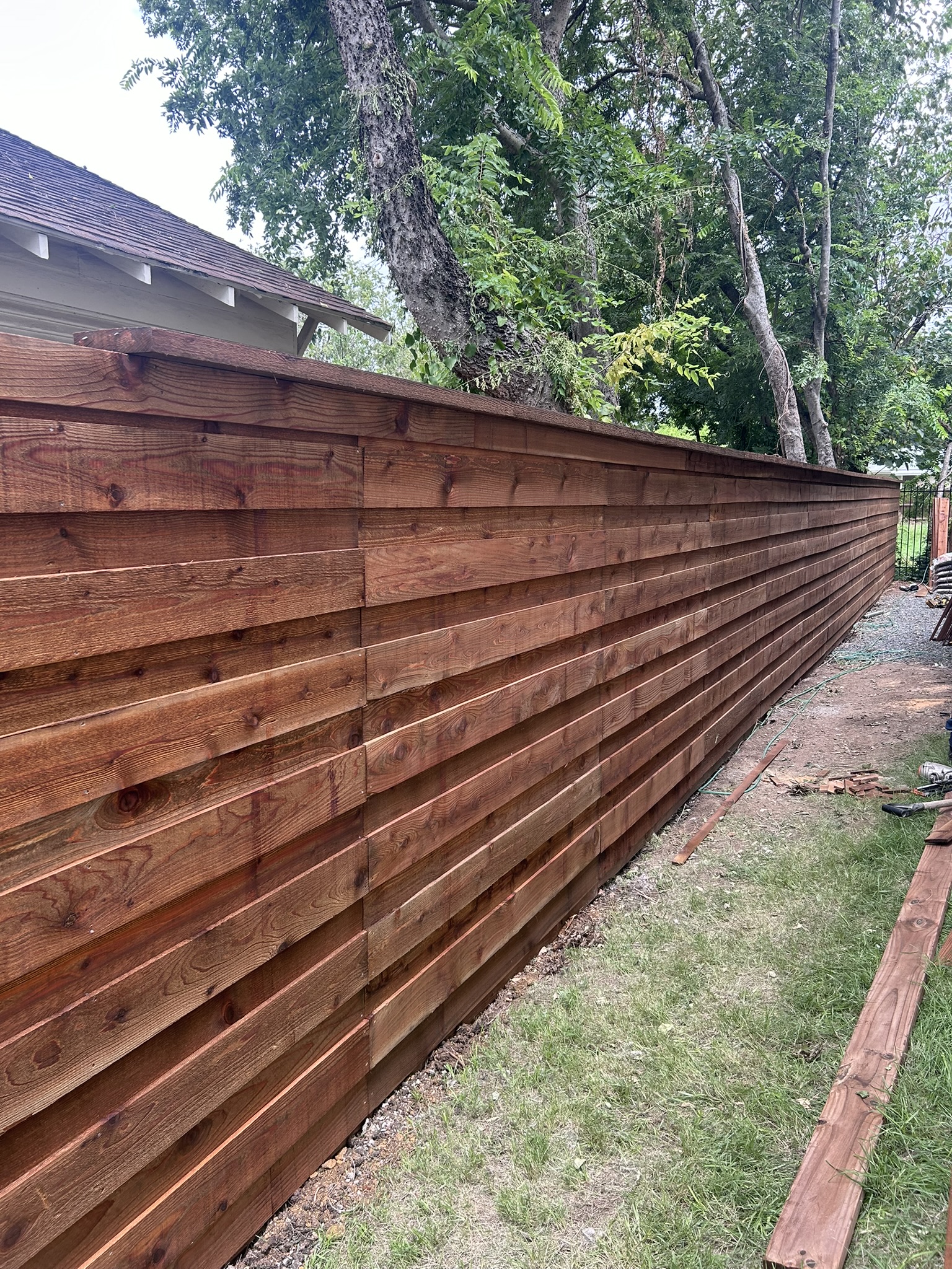 Long horizontal slat cedar privacy fence viewed from the side