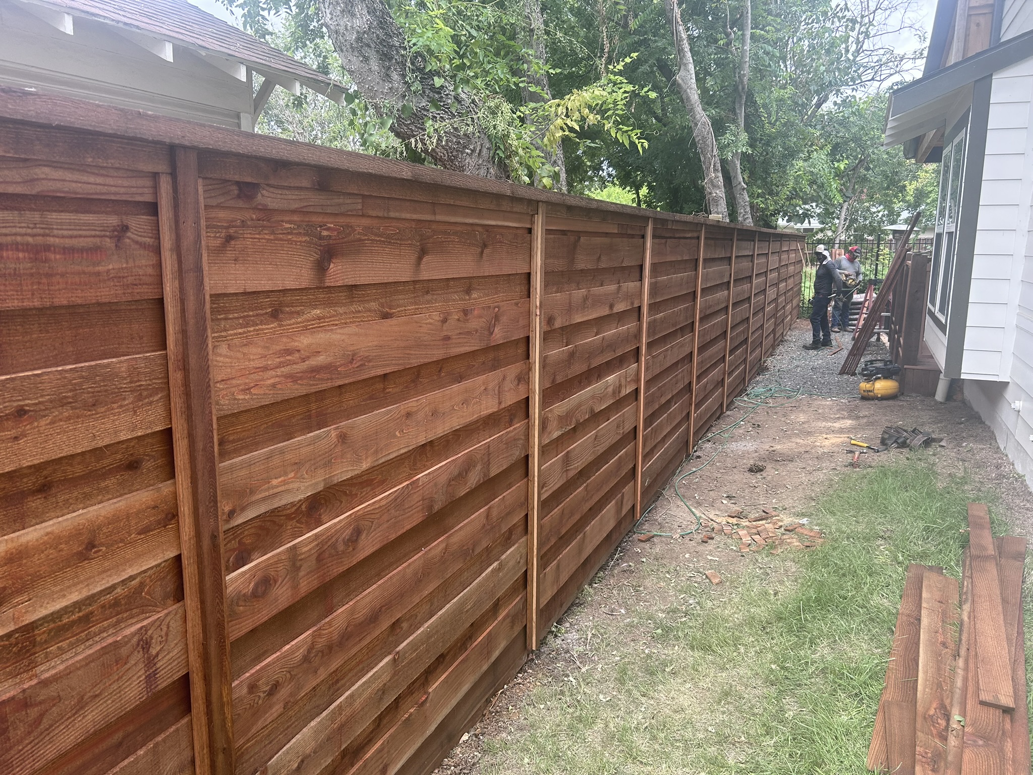 Horizontal slat cedar fence with visible rail framing along a side yard