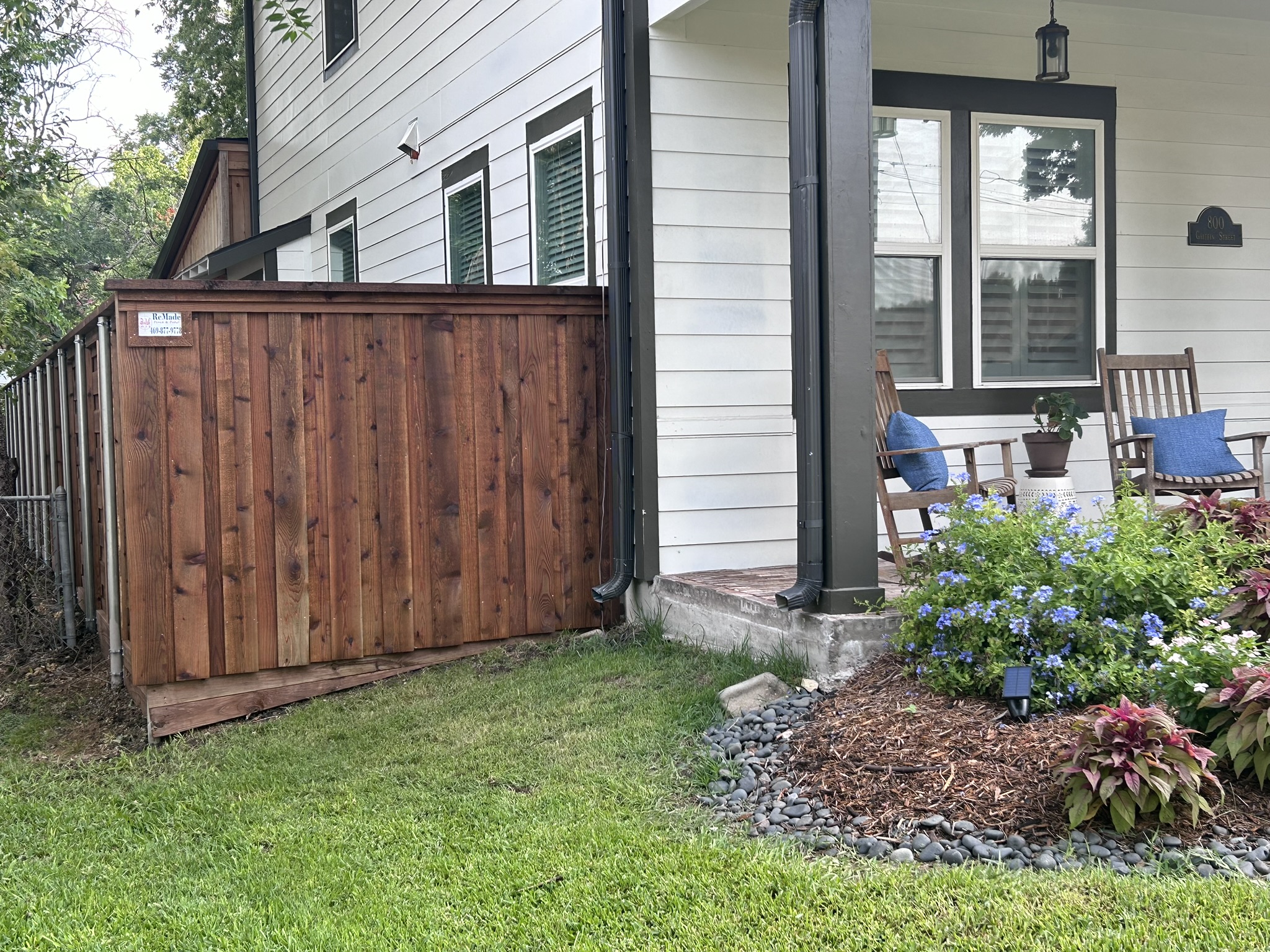 Cedar board-on-board privacy fence section next to a white house with front porch