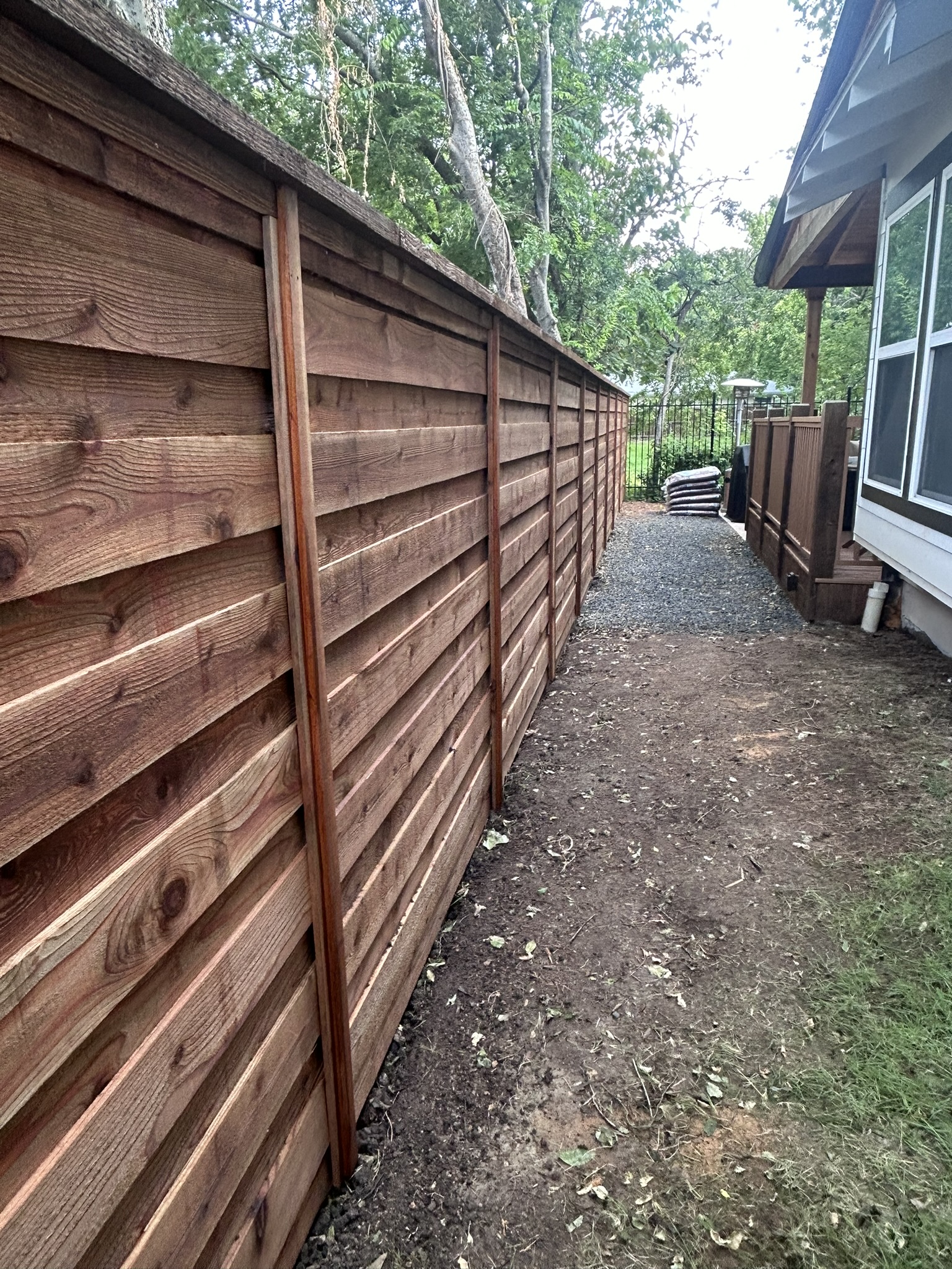 Horizontal slat cedar fence along a dirt side yard path