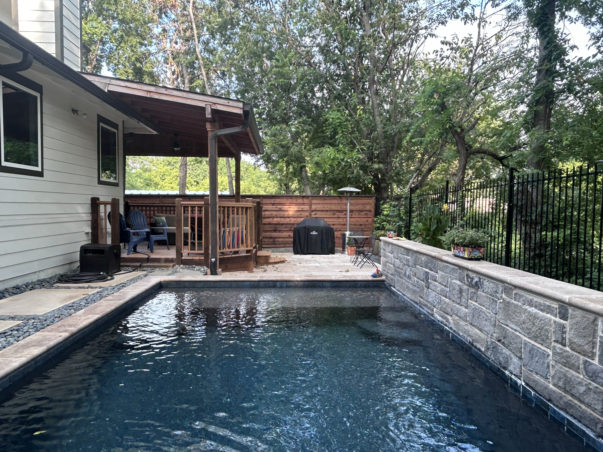 Backyard pool area with horizontal slat cedar fence and covered patio structure