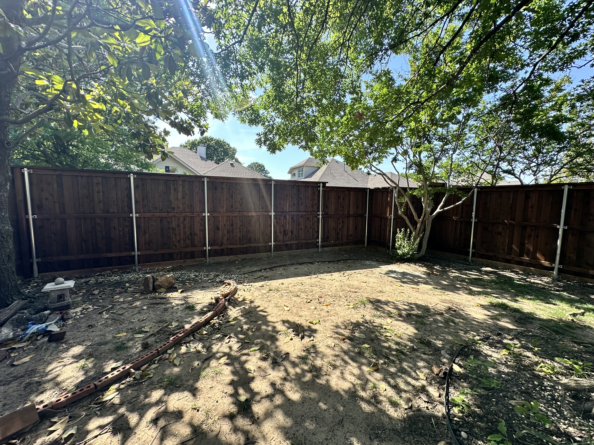 Dark stained cedar privacy fence in a backyard under construction with metal posts