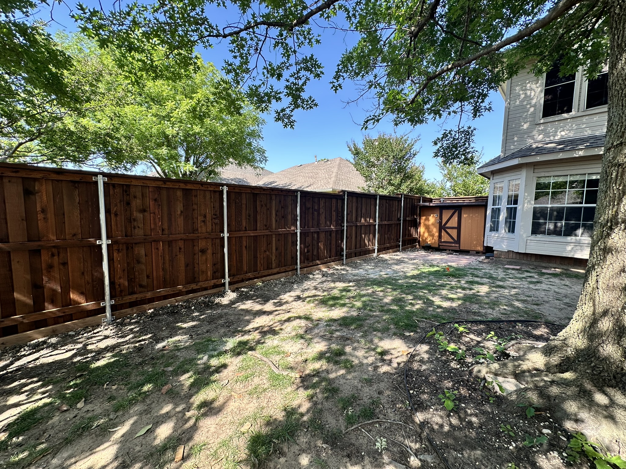 Dark stained cedar privacy fence with wood gate in a backyard