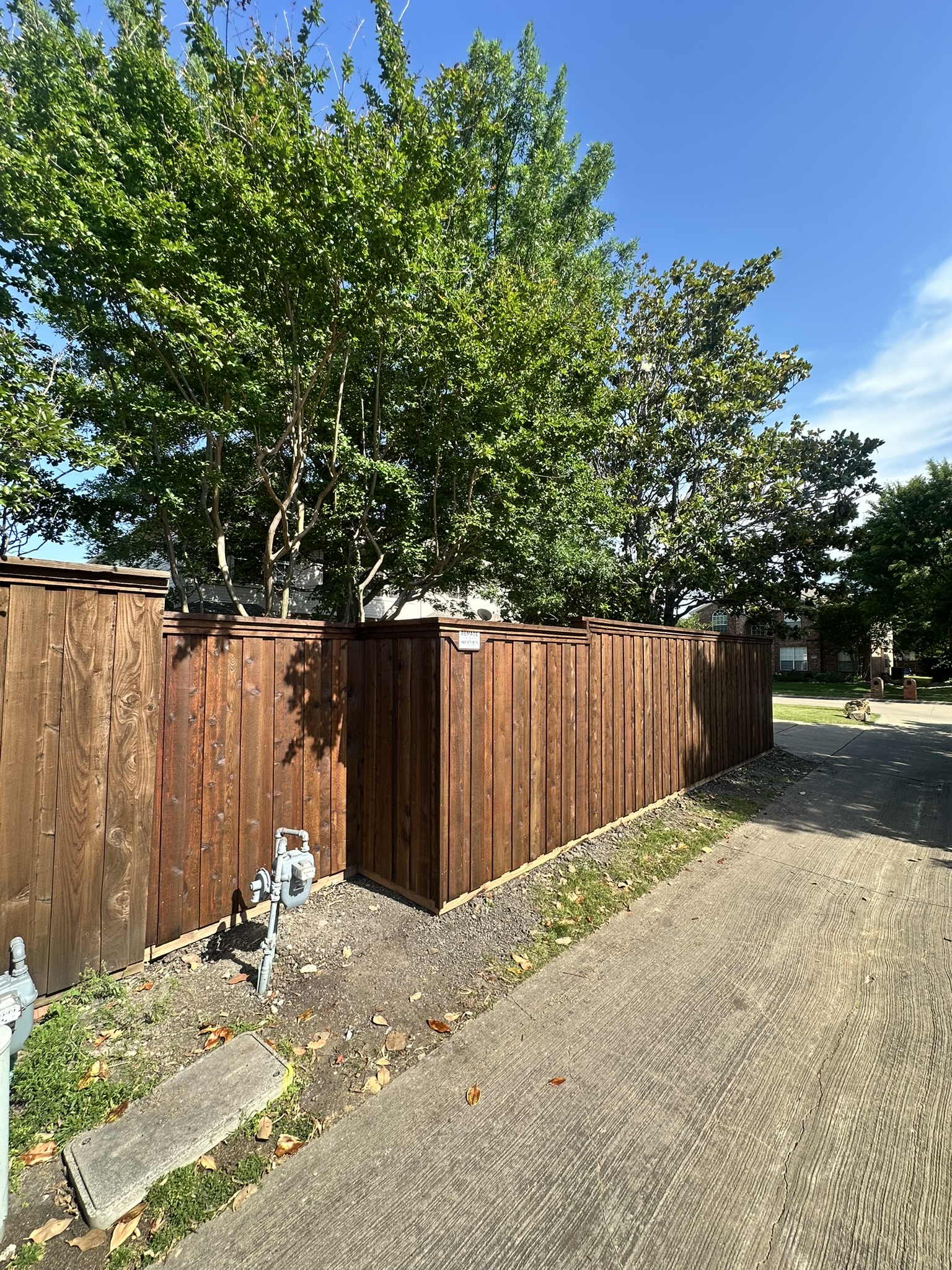 Stained cedar board-on-board fence at a corner lot viewed from sidewalk