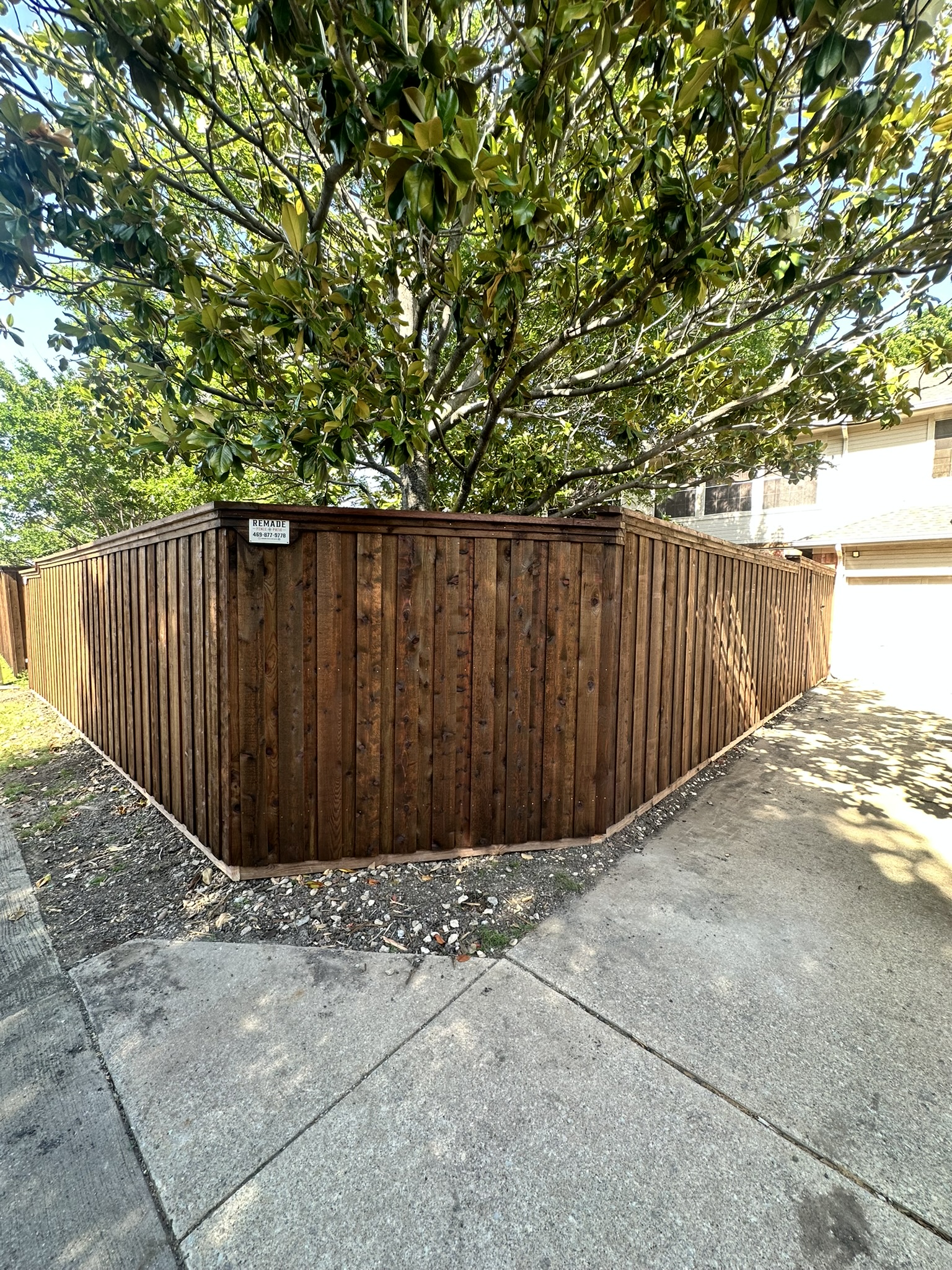 Stained cedar privacy fence in a narrow side yard beside a brick house