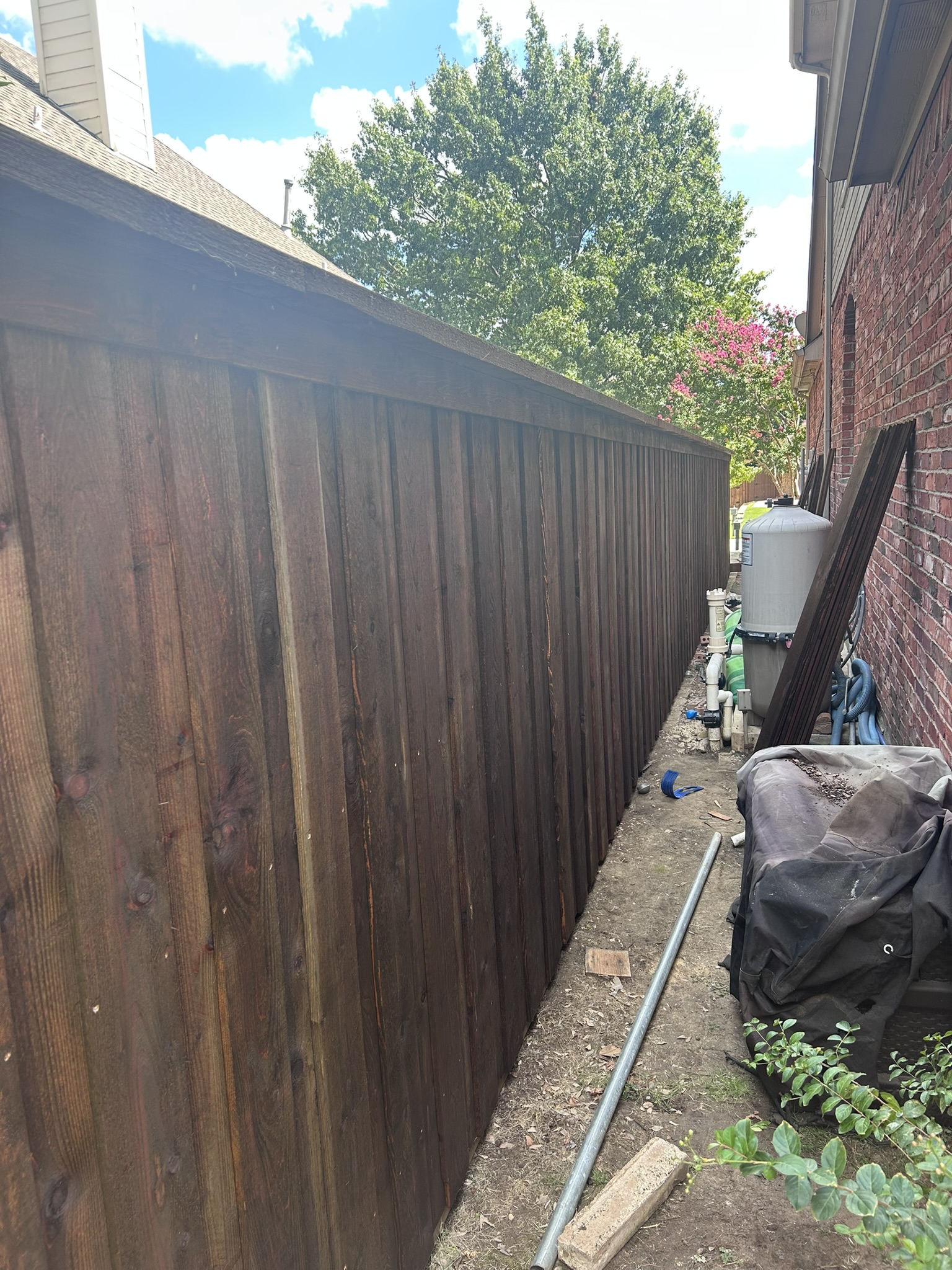Dark stained cedar board-on-board fence along a side yard