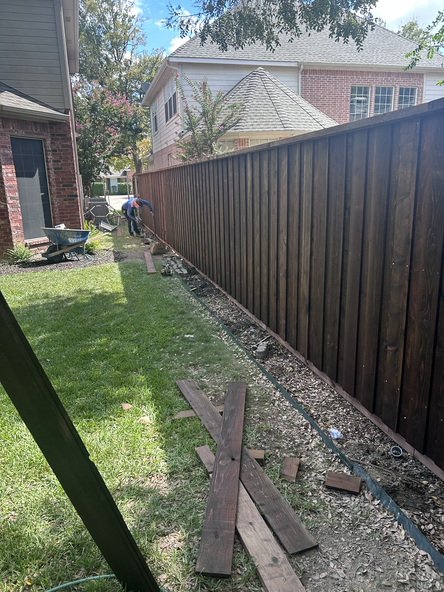 Dark stained cedar privacy fence running along a backyard with fresh landscaping