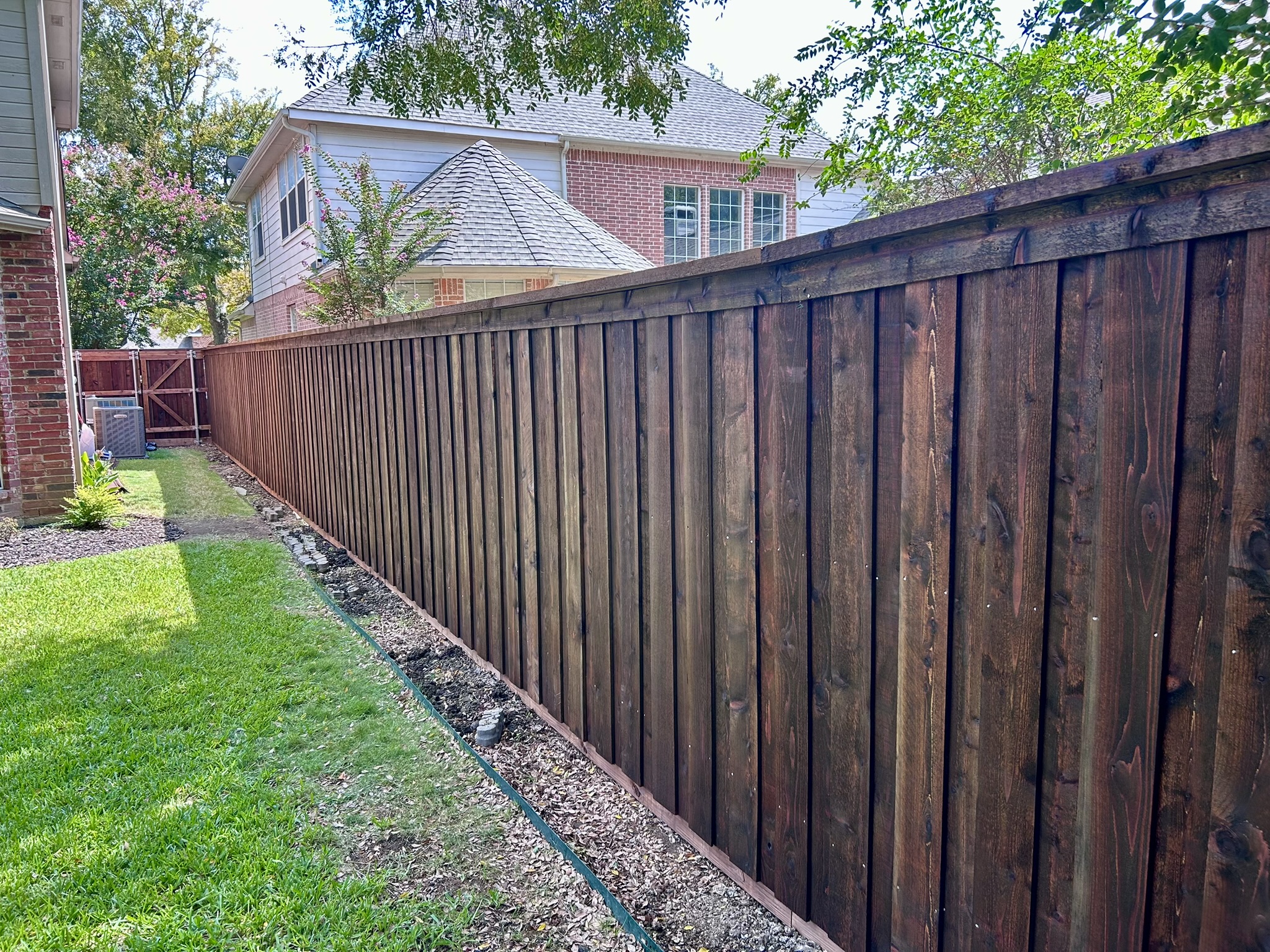 Dark stained cedar privacy fence in a narrow side yard next to pool equipment