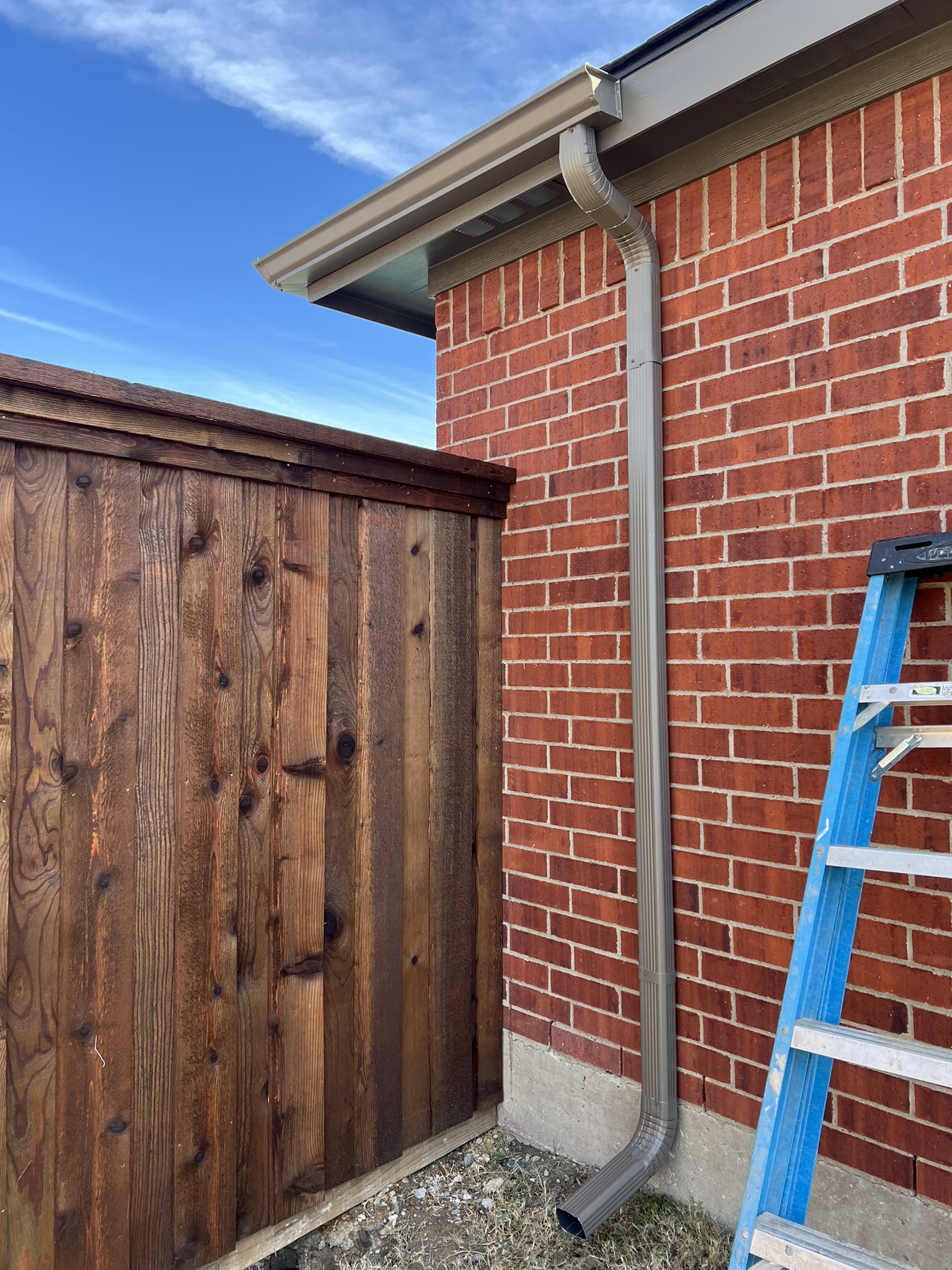 Cedar wood gate with black hardware next to a brick wall
