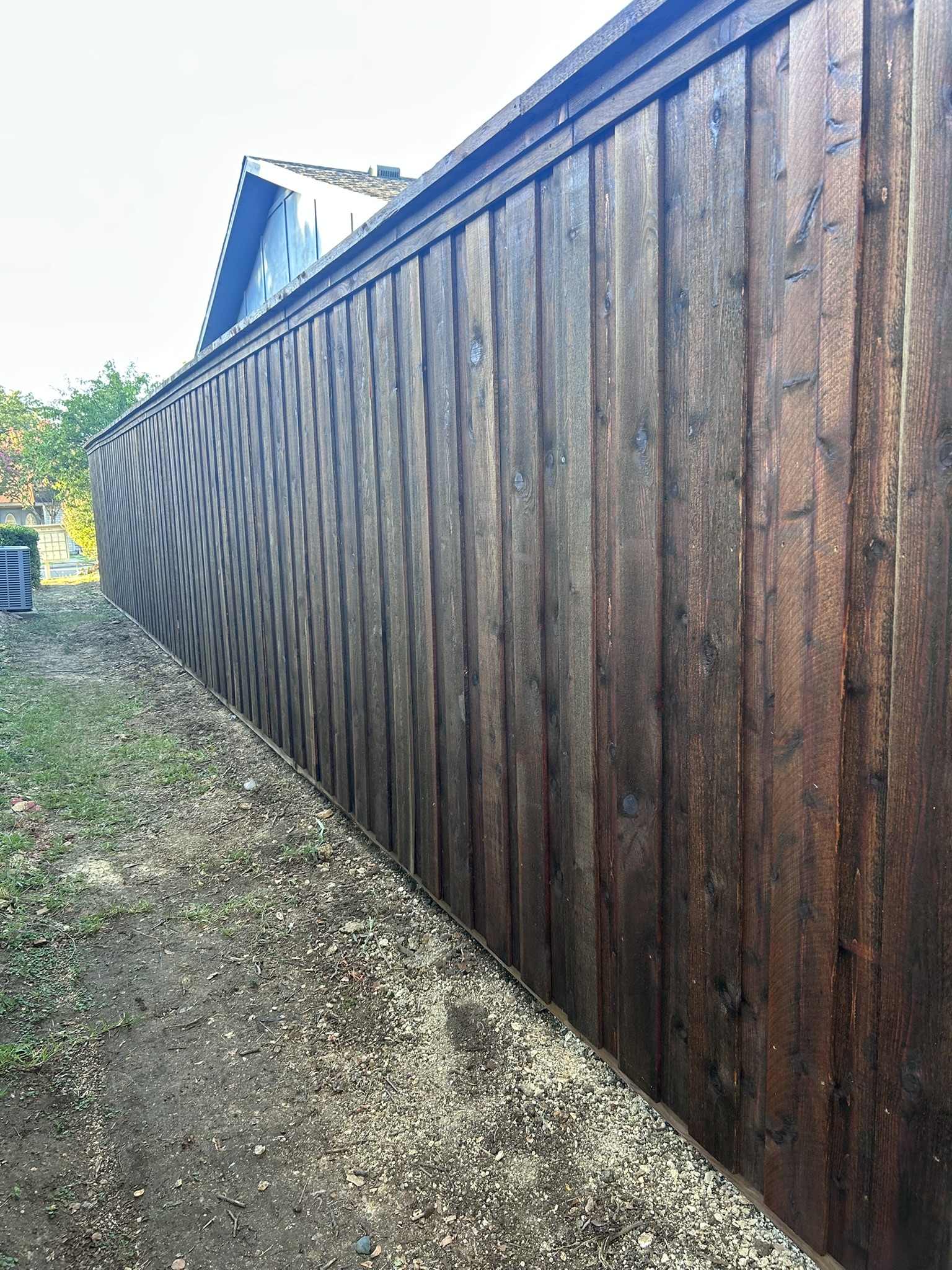 Stained cedar board-on-board privacy fence along a residential property corner
