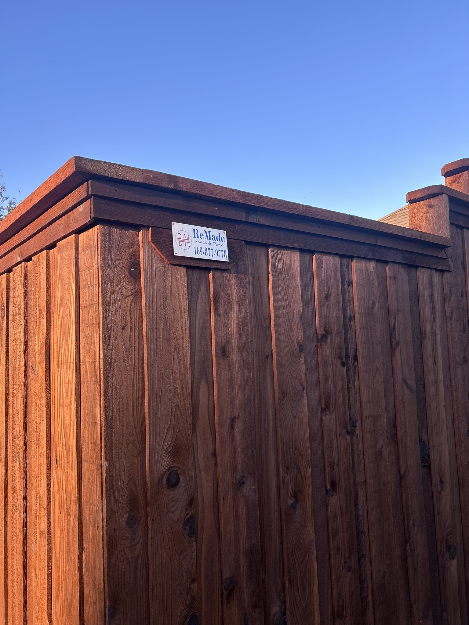 Close-up of dark-stained cedar privacy fence with decorative cap rail and post caps