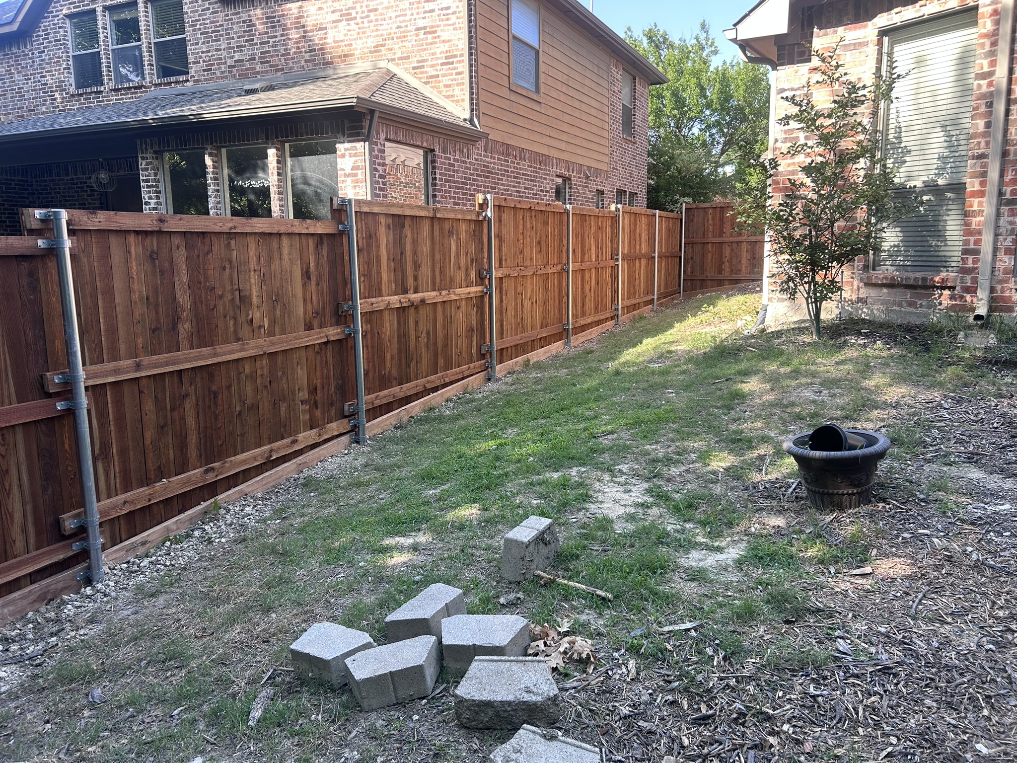 Cedar privacy fence with metal posts between two homes with pavers on ground