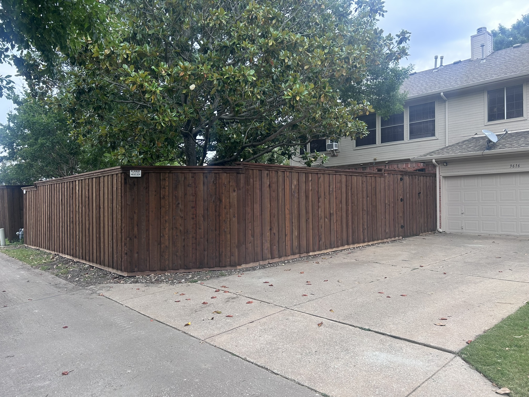 Dark-stained cedar board-on-board privacy fence with cap rail along a driveway