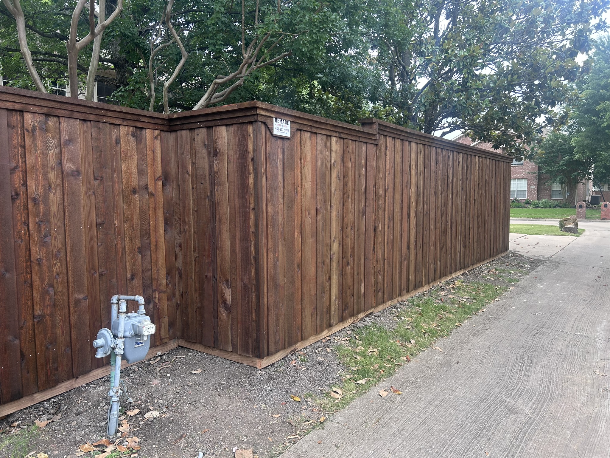 Dark-stained cedar privacy fence with decorative cap and post caps along alleyway
