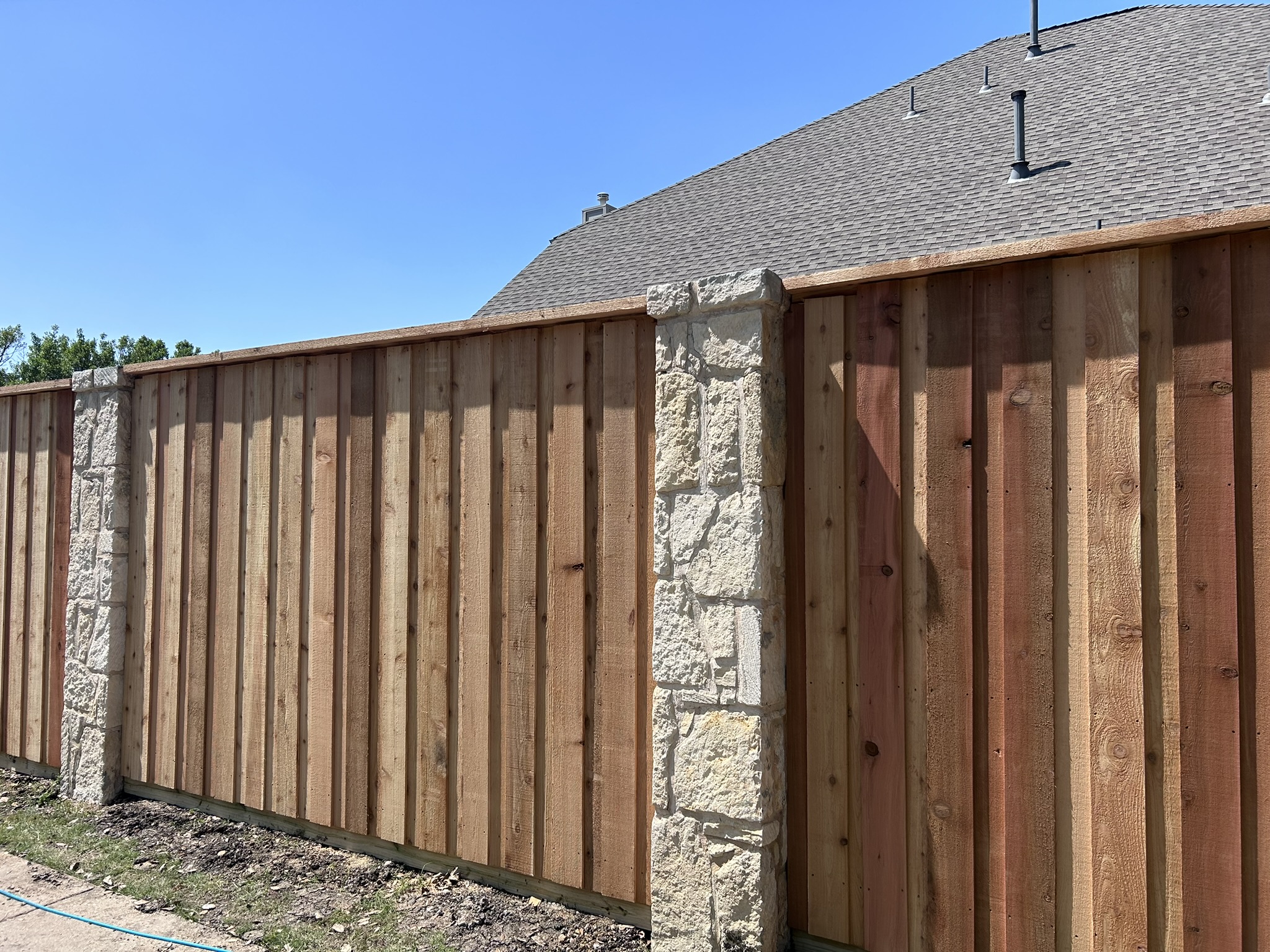 Close-up of new cedar board-on-board fence panels between stone pillar columns