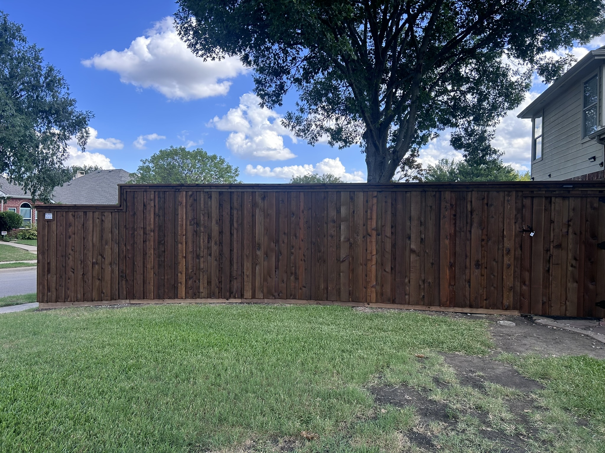 Dark-stained cedar privacy fence with cap rail and integrated gate across front yard