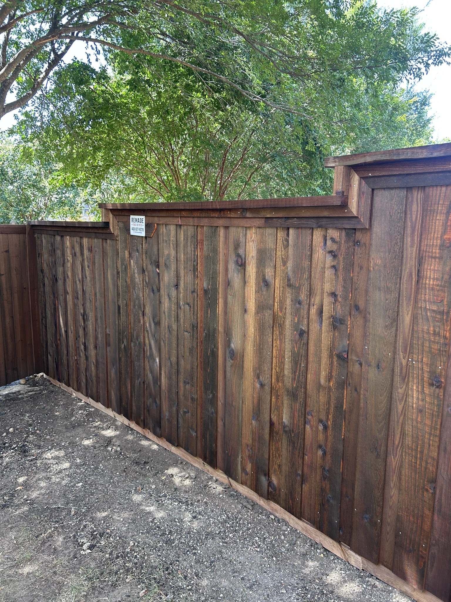 Dark-stained cedar board-on-board privacy fence with cap rail along side yard