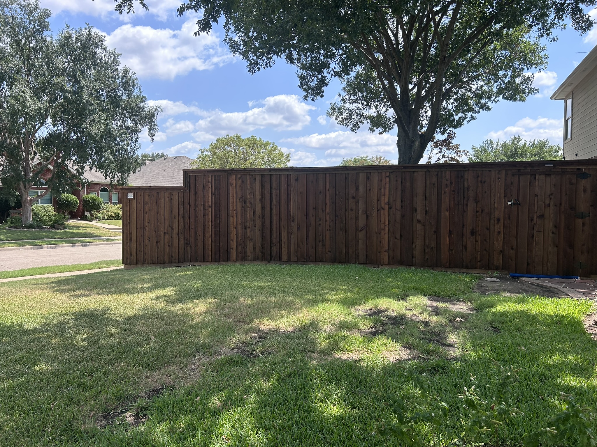 Long dark-stained board-on-board wood privacy fence along residential street