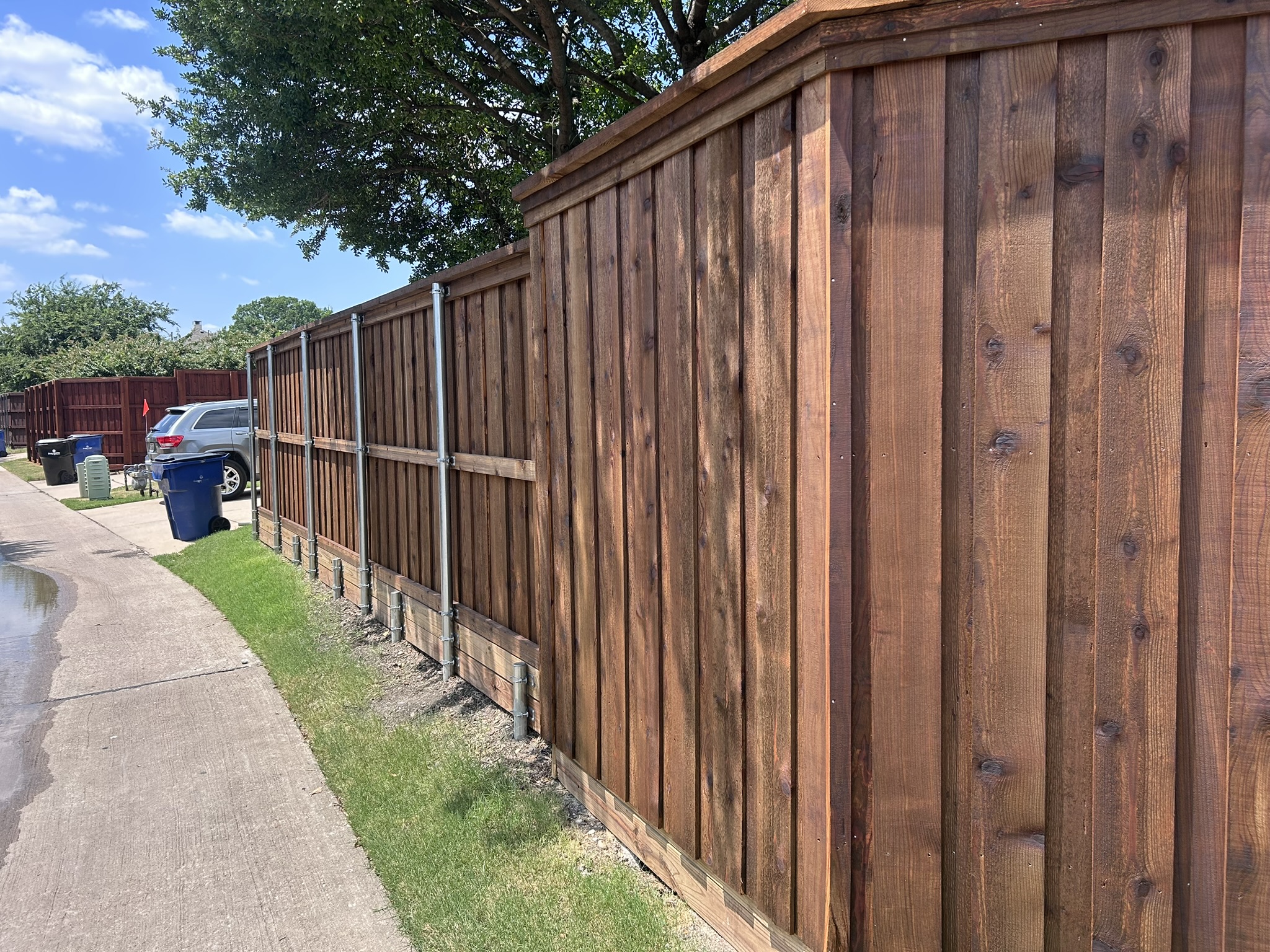 Back side of stained cedar privacy fence showing metal posts and horizontal rails