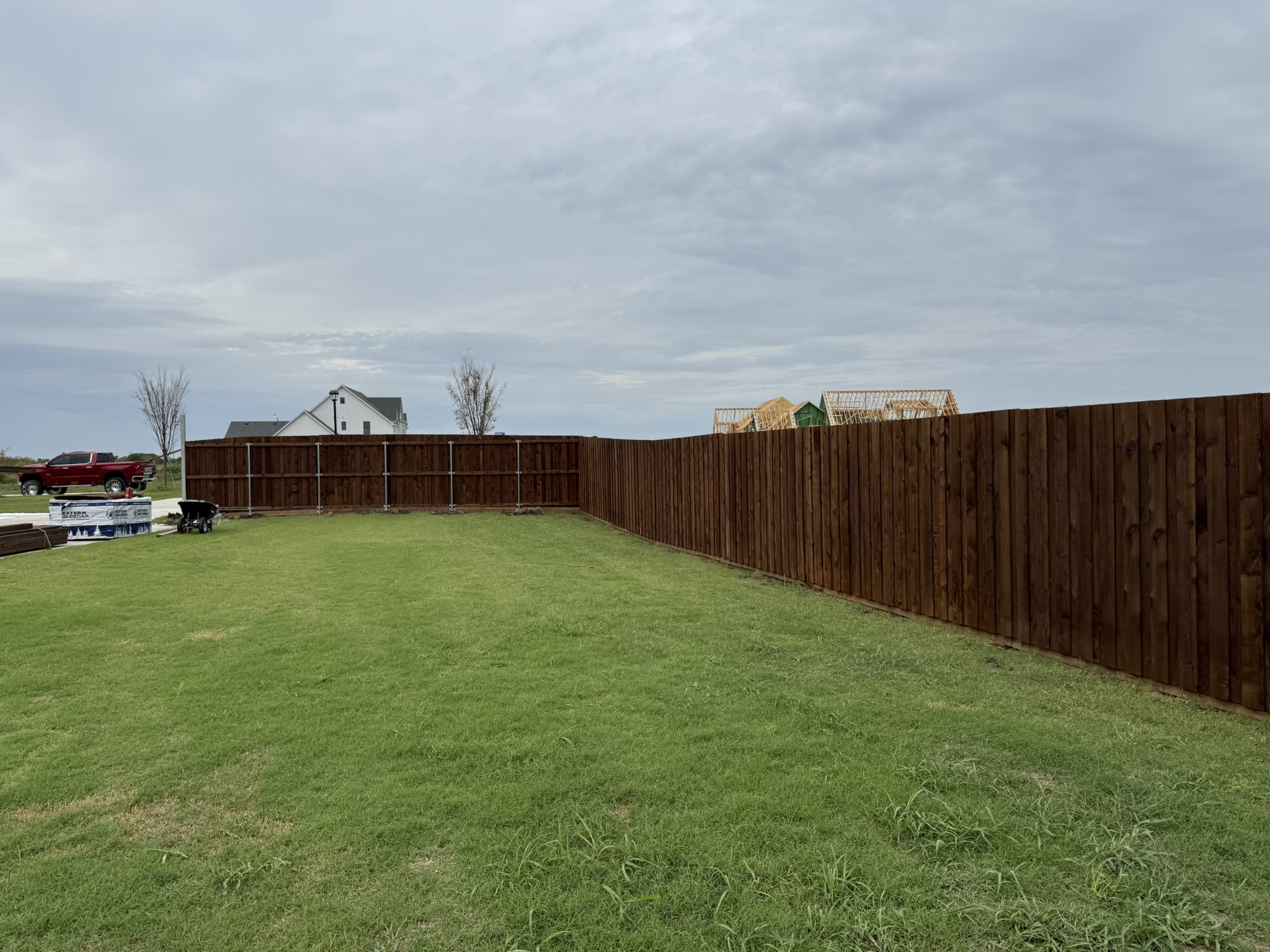 Long stained cedar privacy fence enclosing new construction backyard