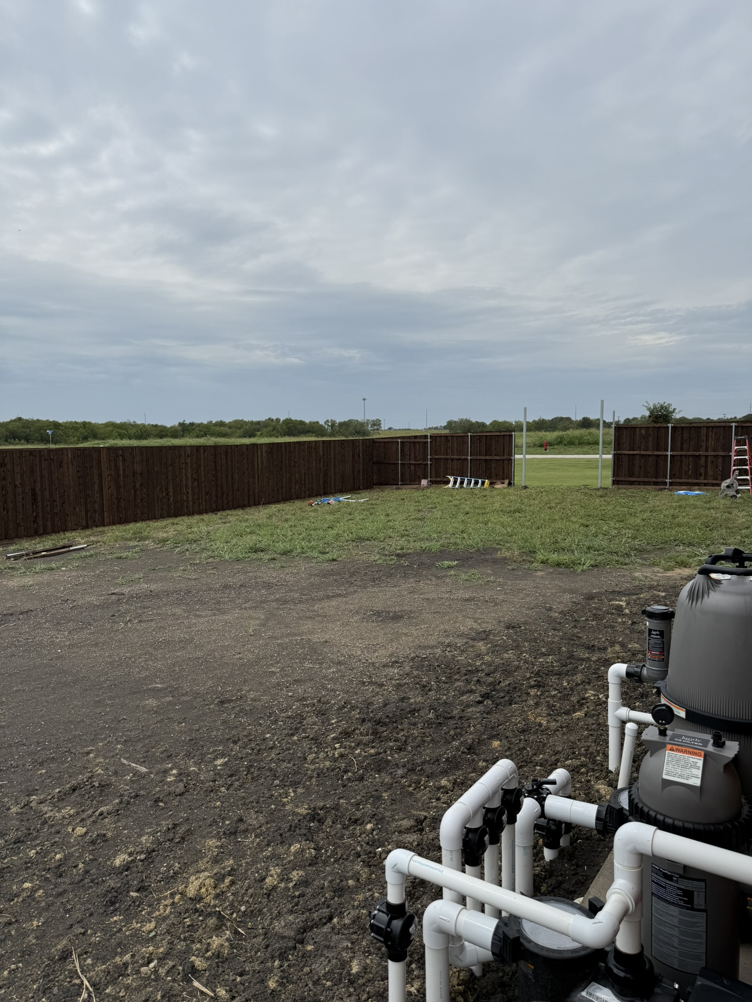Stained cedar privacy fence under construction in large backyard