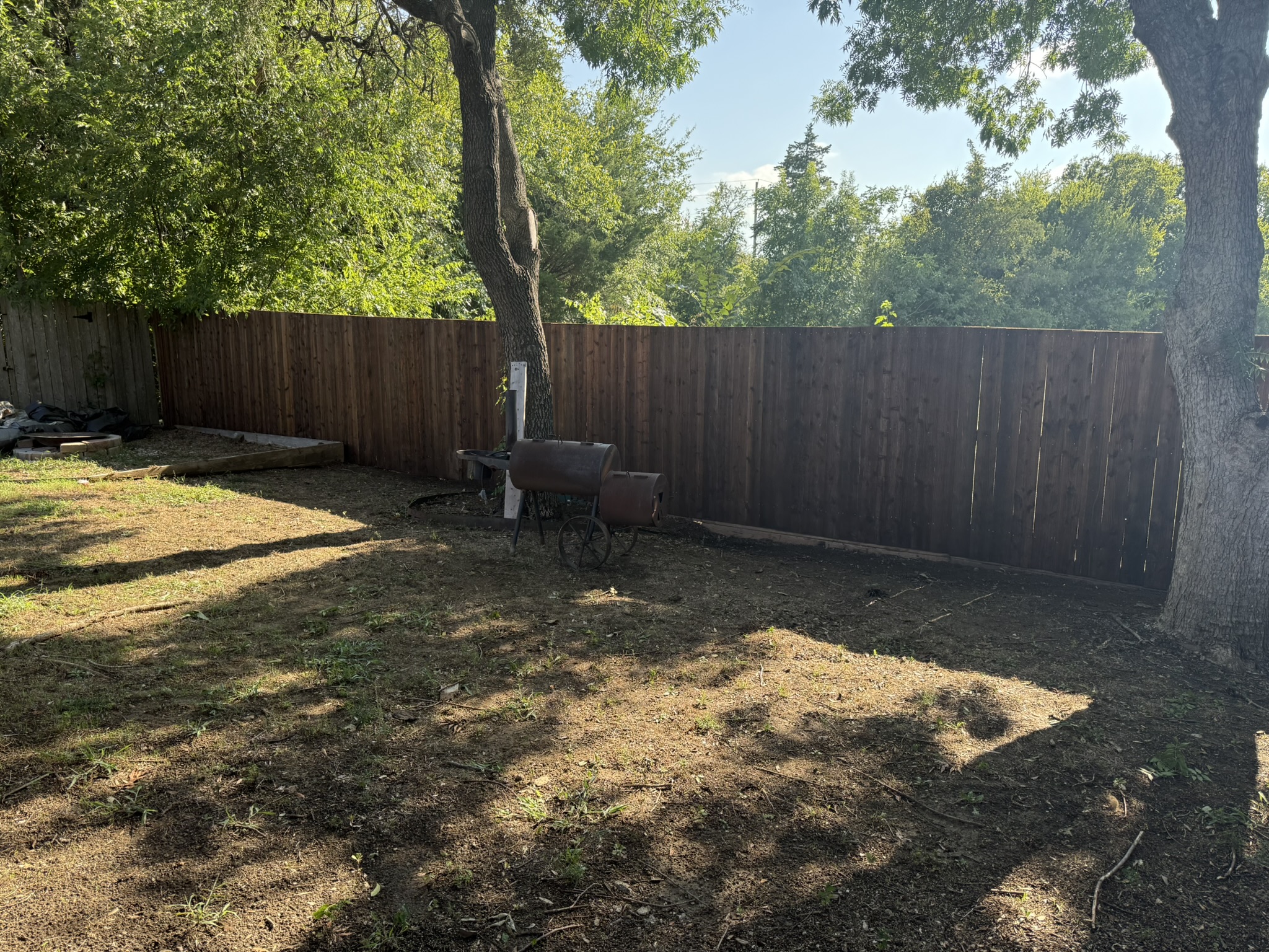 Stained cedar board-on-board privacy fence with metal posts enclosing backyard corner
