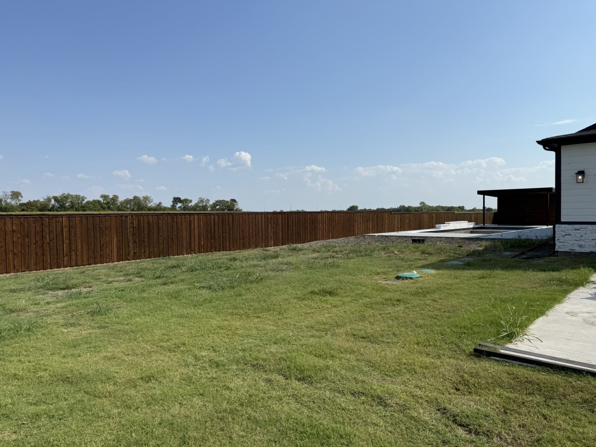 Long stained cedar board-on-board privacy fence spanning wide backyard