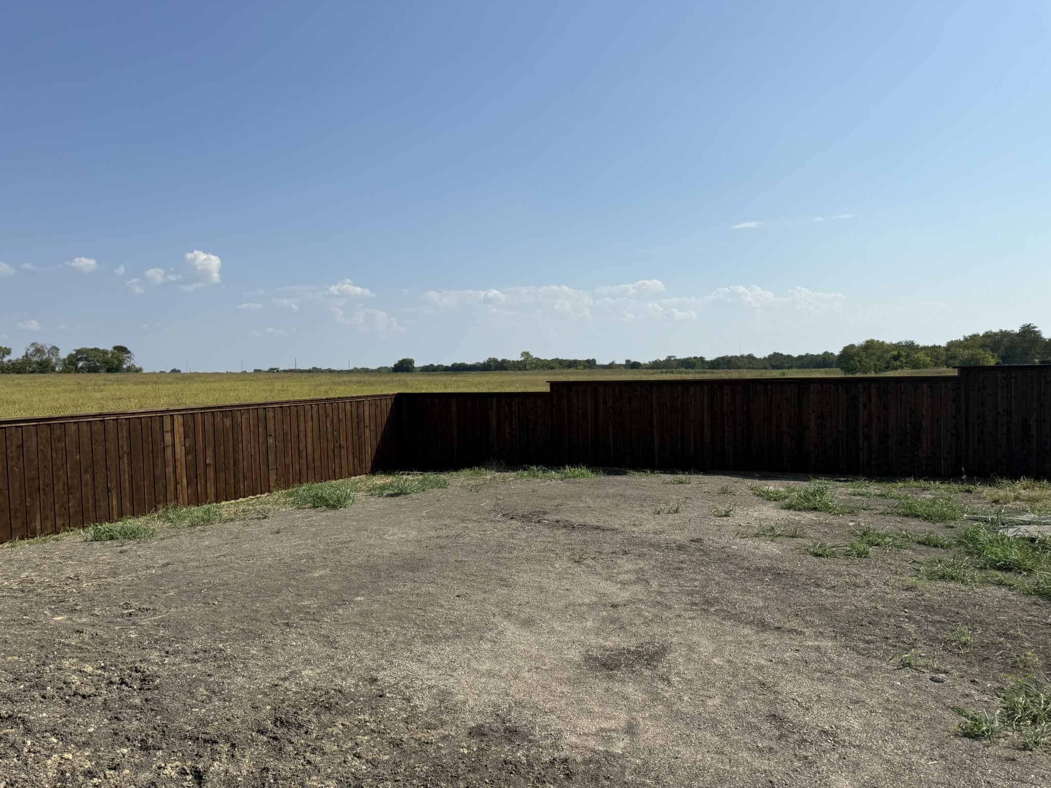 Stained cedar privacy fence with metal posts viewed from backyard