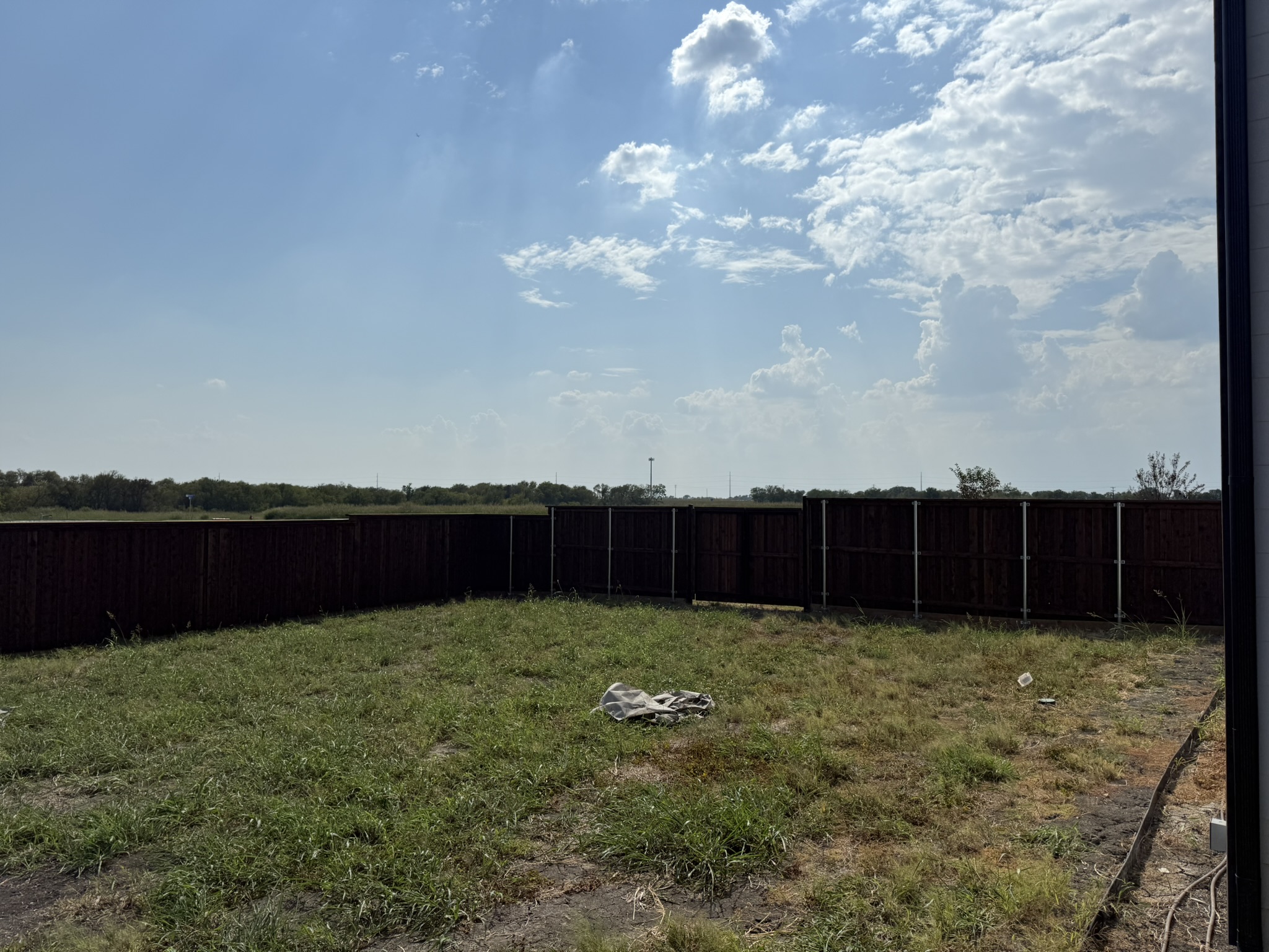 Stained cedar board-on-board privacy fence with gate alongside modern home