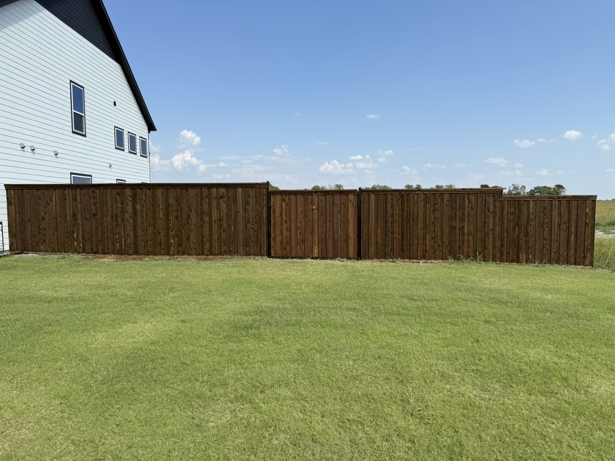 Stained cedar privacy fence with sliding wood gate across driveway