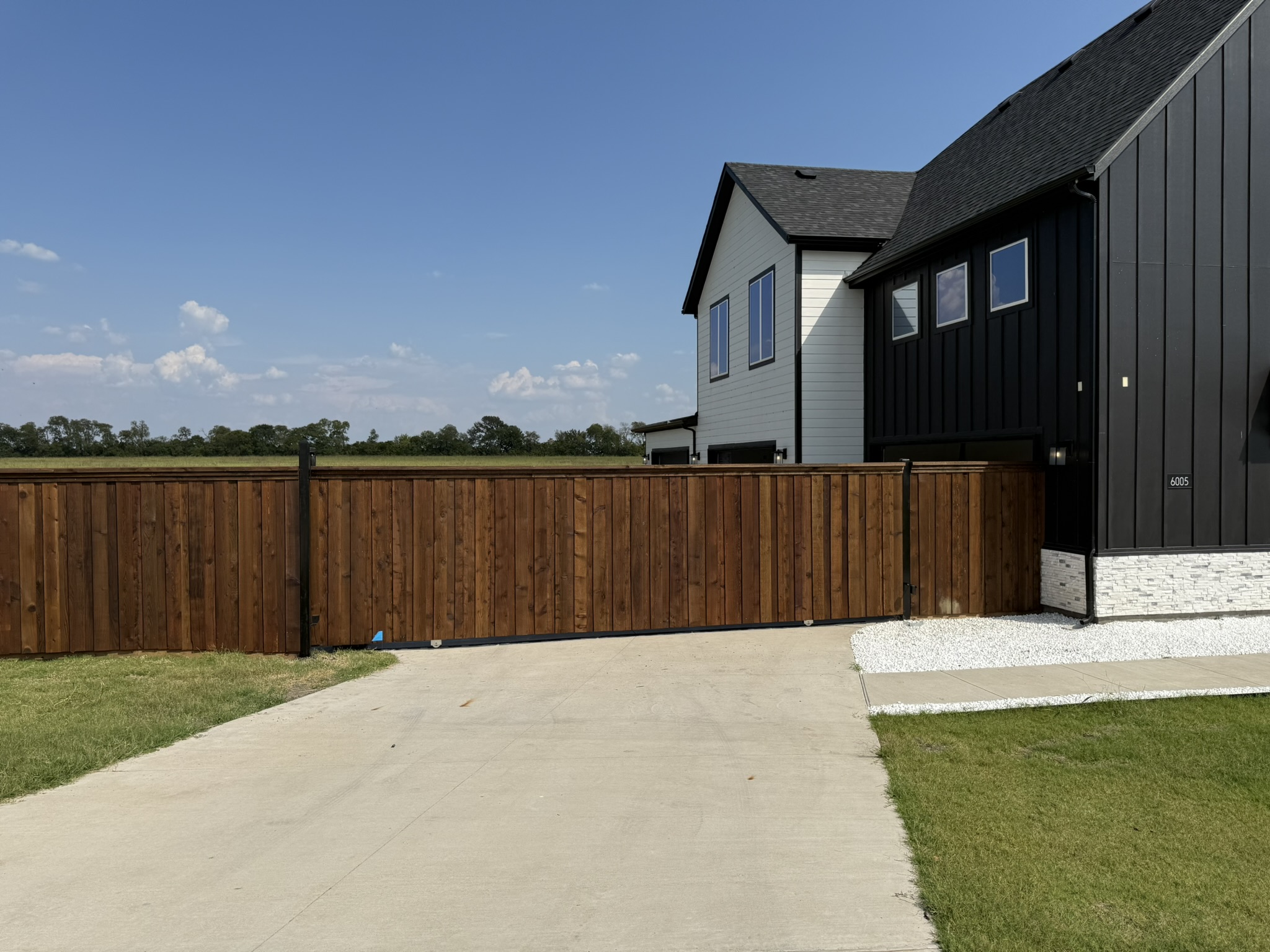 Stained cedar privacy fence with black metal post and lamppost along driveway